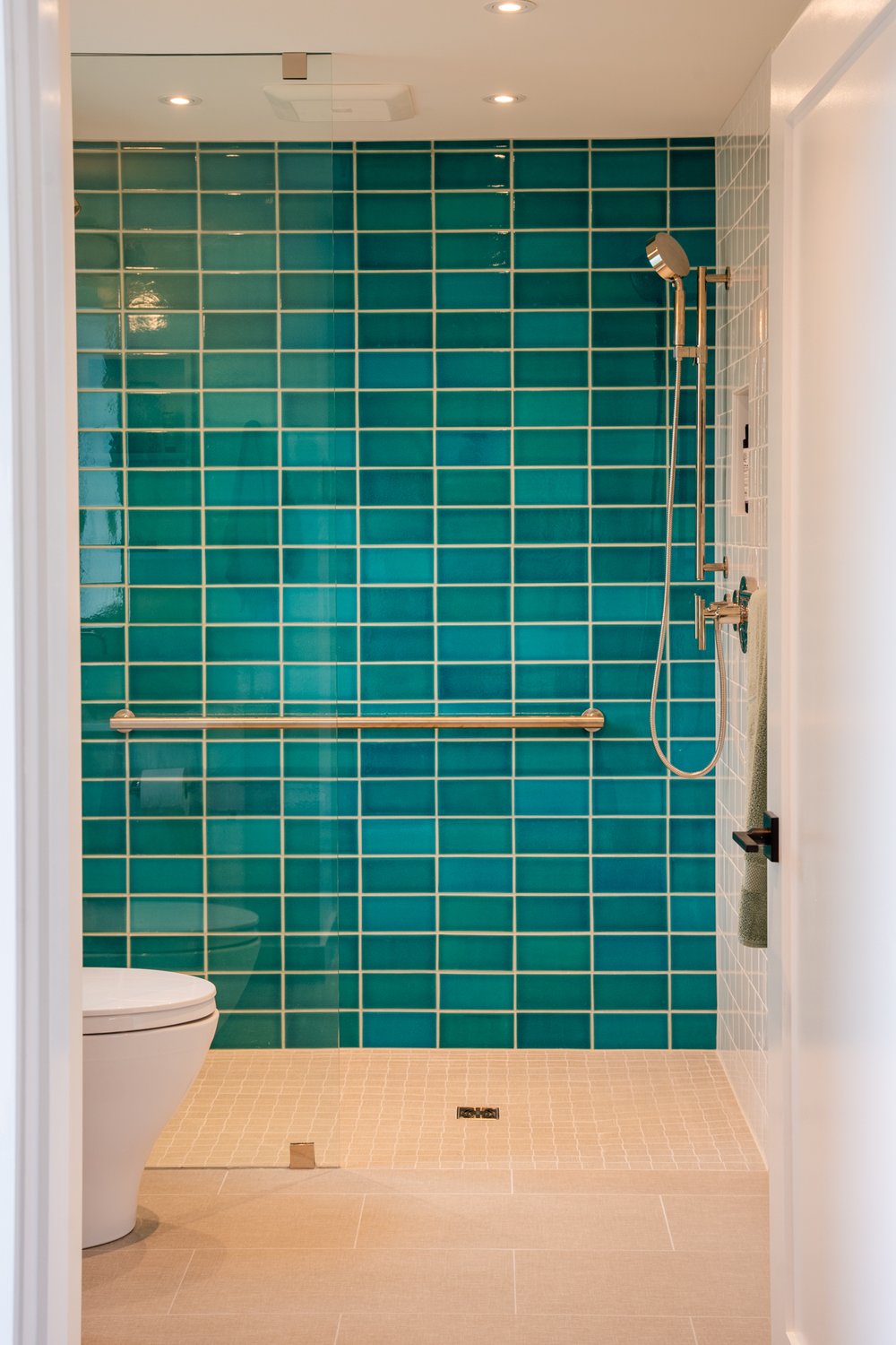 Note the easy mobility features, such as a curb-free shower with a grab bar and wide access, and the Tropics blue crackle tiles by Heath Ceramics.