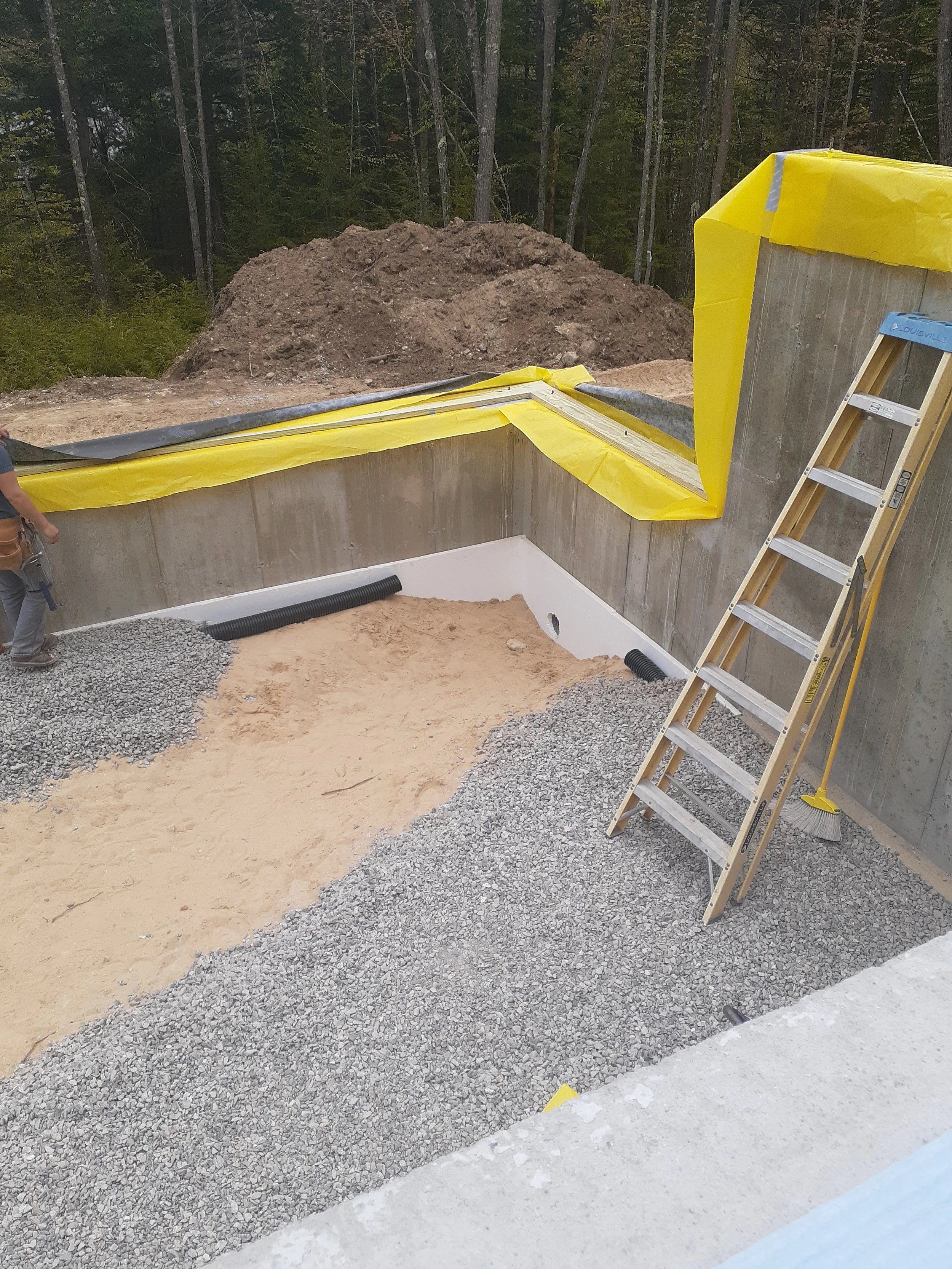 Partially constructed basement with a drainage and radon mitigation system being installed