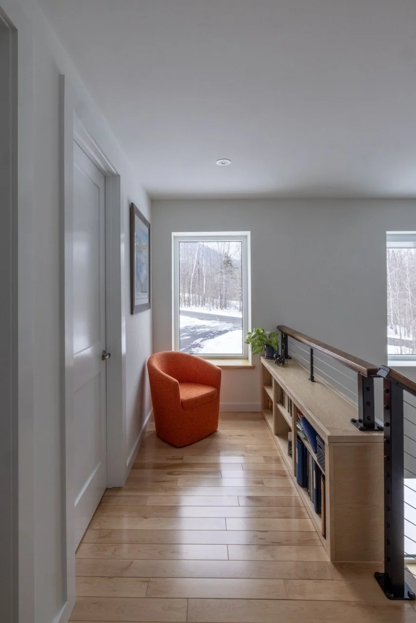 At the top of the staircase, more built in bookcases and an orange chair create a reading nook.