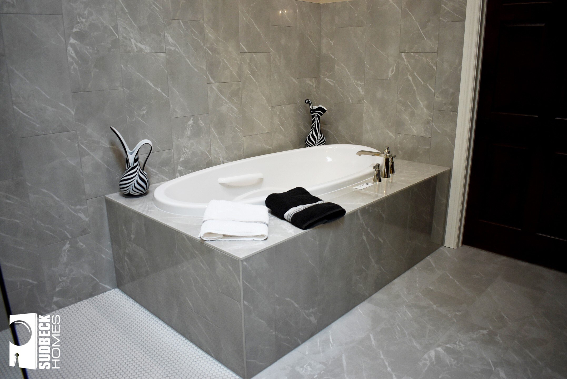 Your space should speak to your personality and lifestyle. A zero-entry shower with gold accents, mable covered bath, and coffered ceilings all add intrigue to the space! We're in love with the simplicity of the space but how it catches your eye ever