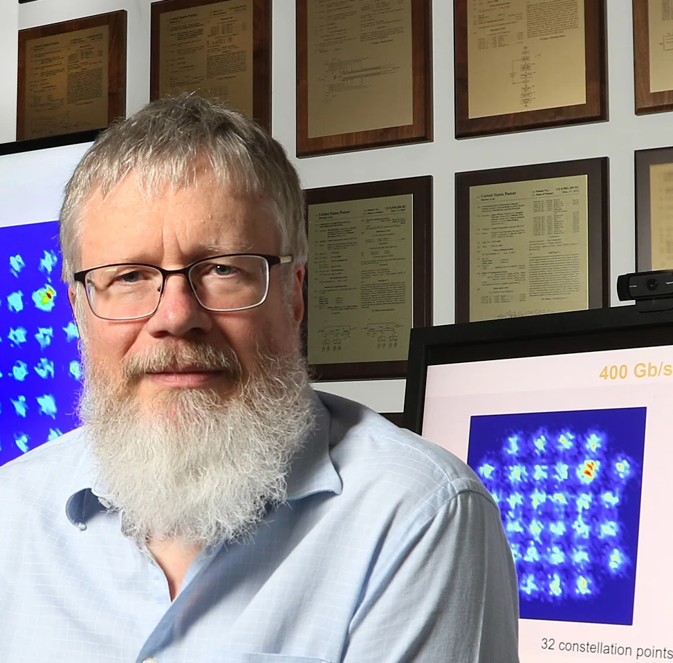 Kim Roberts of Ciena. On the wall are some of his 160 patents while on the screen is an image of a 32-point constellation produced by the WaveLogic Ai coherent modem. Source: Ciena.