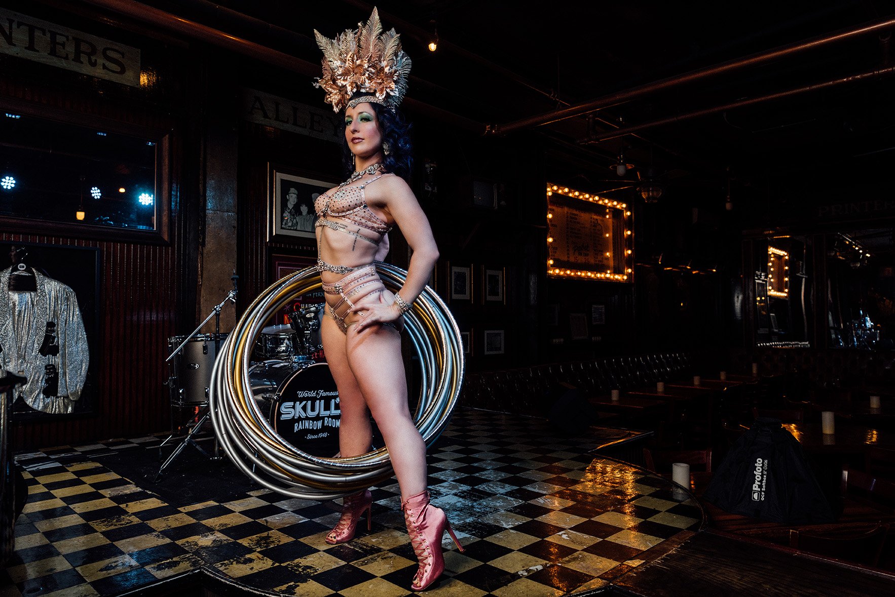 Burlesque performer poses in a headdress while holding several hula hoops.