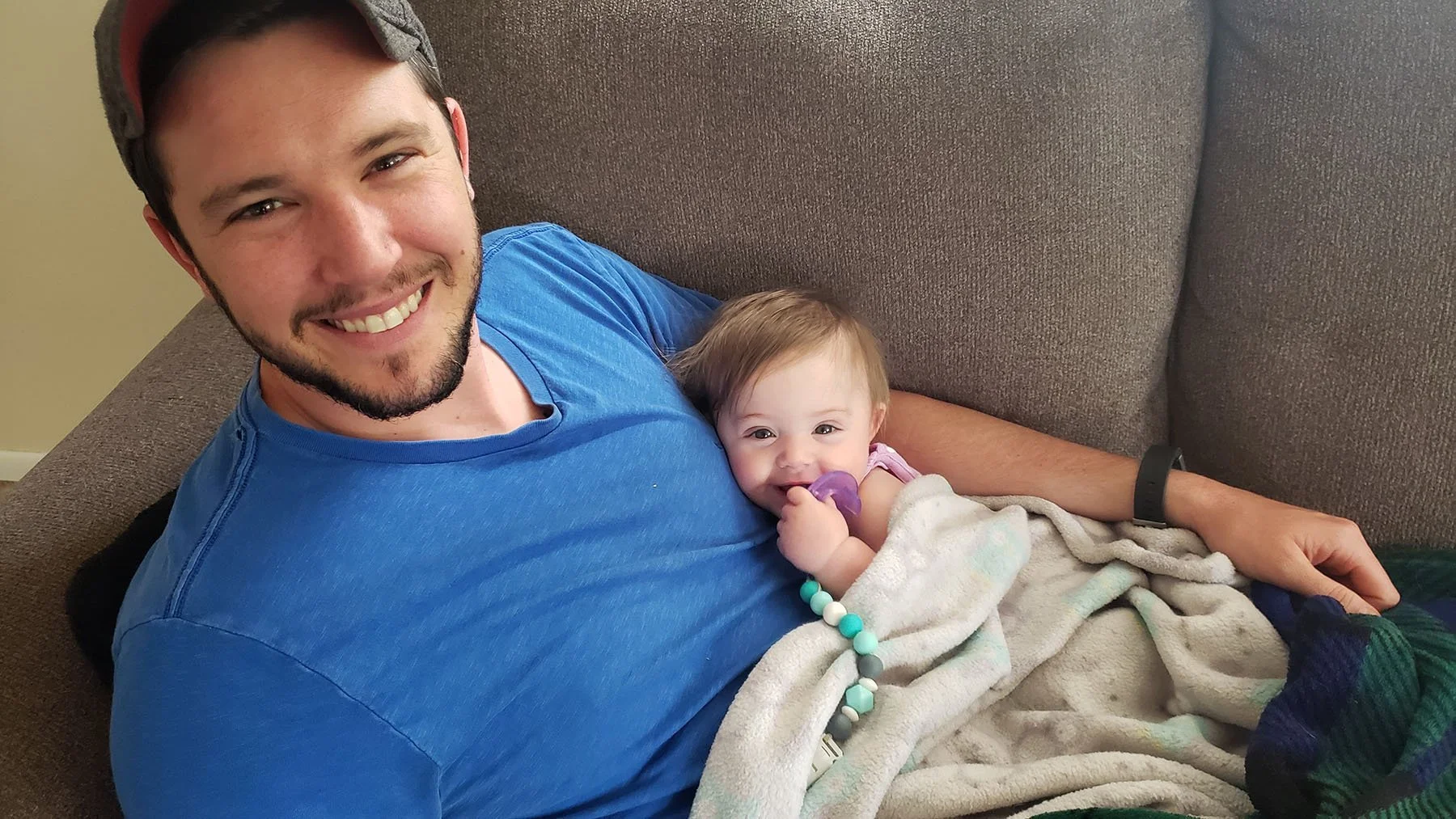 Father and young daughter relaxing together on a couch at home.
