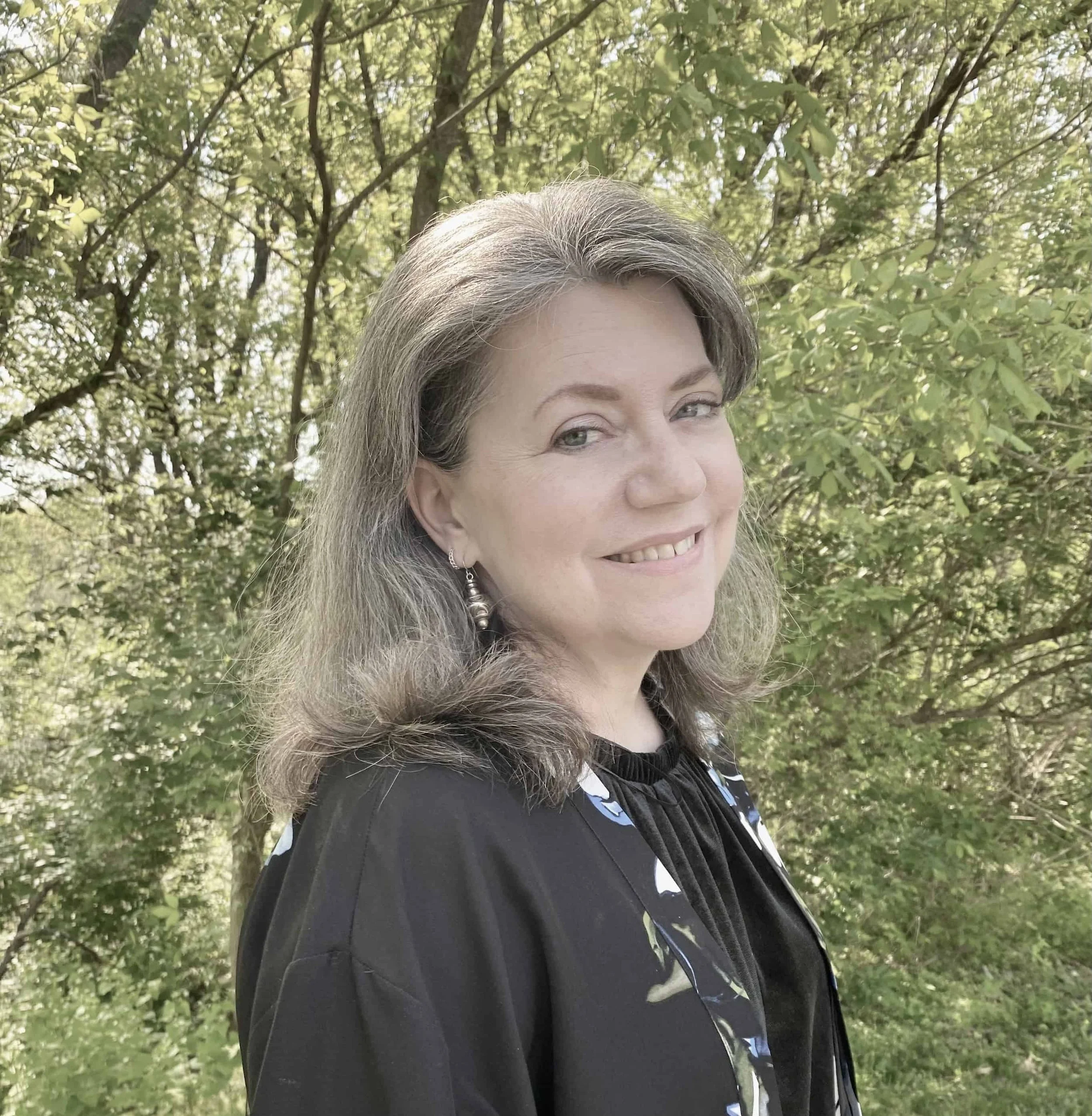 “Silver-haired woman smiling for a portrait outdoors.