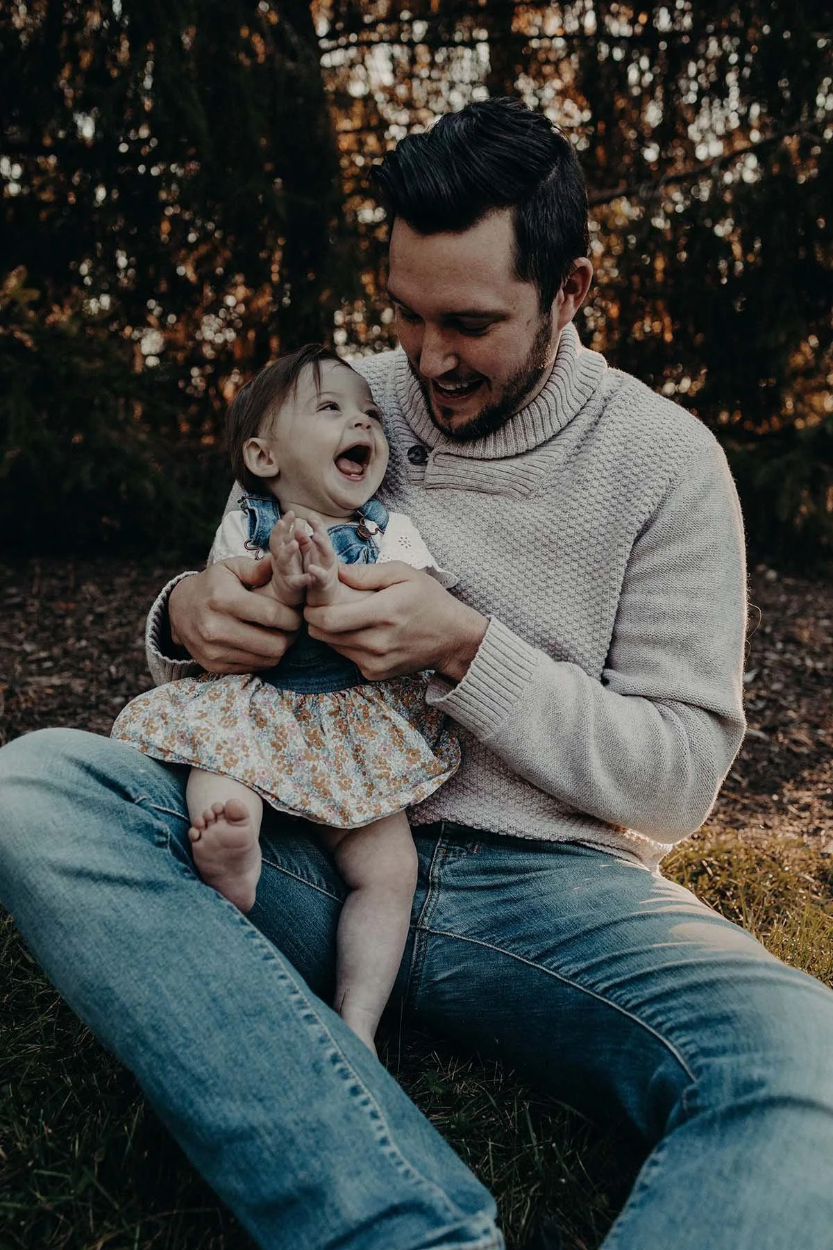 Father and young daughter laughing together outdoors.