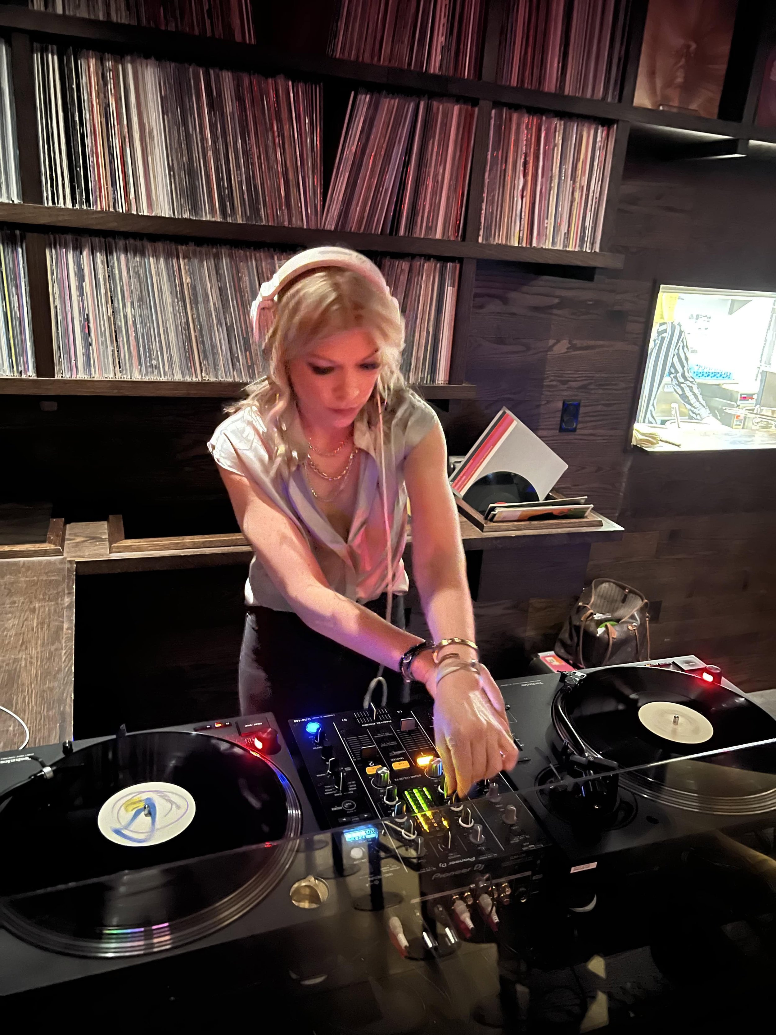 Woman DJs at a mixing table while concentrating on music controls during a live set.