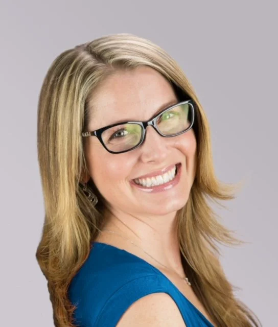Smiling woman in glasses poses for headshot.