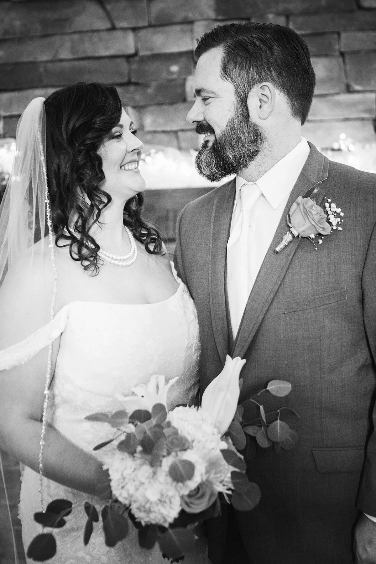 Bride and groom smiling at each other during their wedding ceremony.