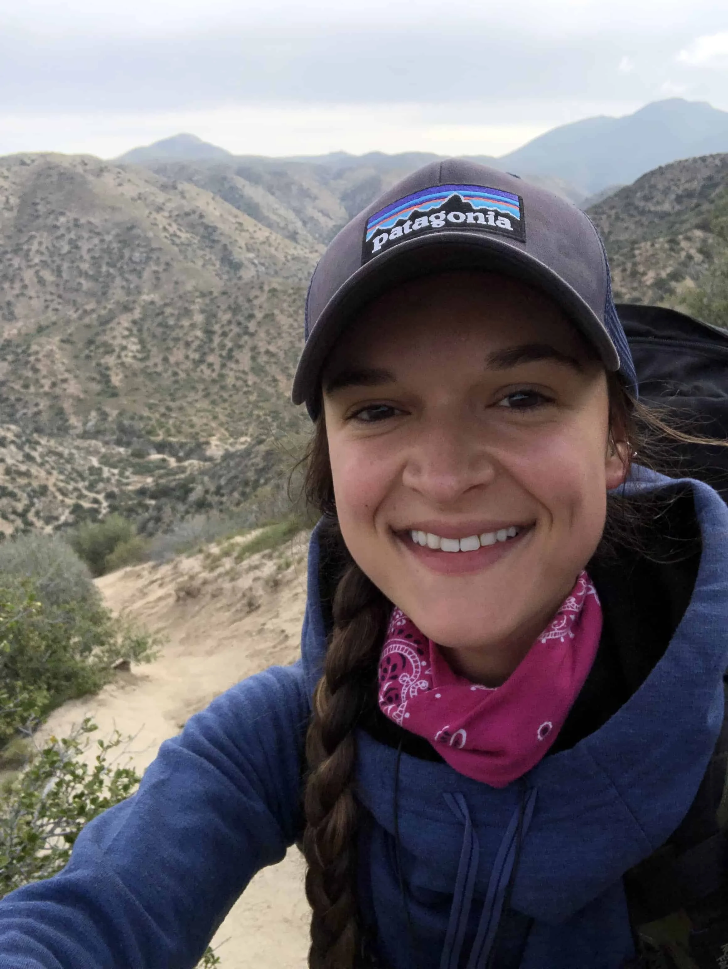 Woman smiling at the camera during a hiking selfie.