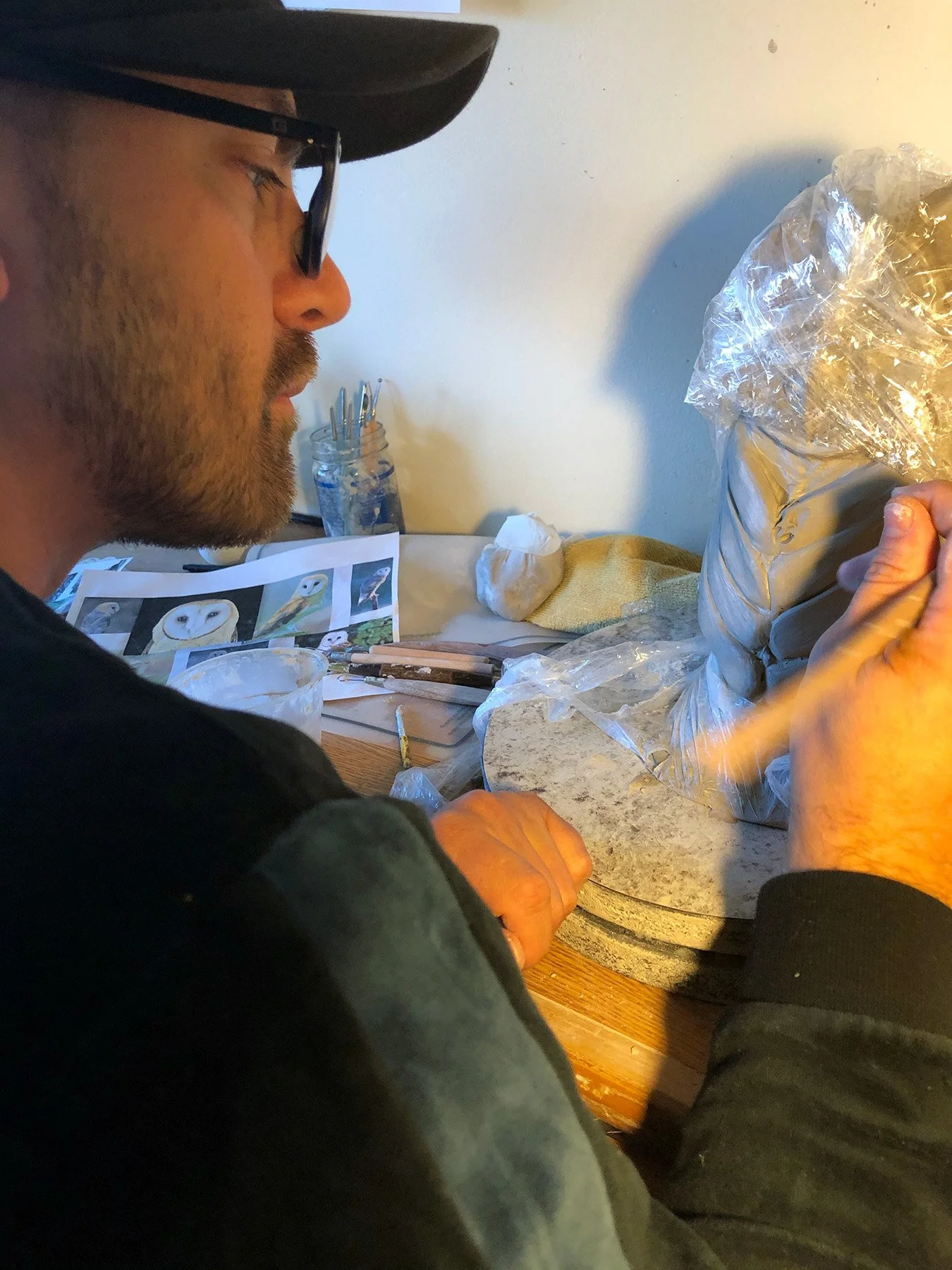Ceramic artist sculpting clay by hand with carving tools in a contemporary art studio.