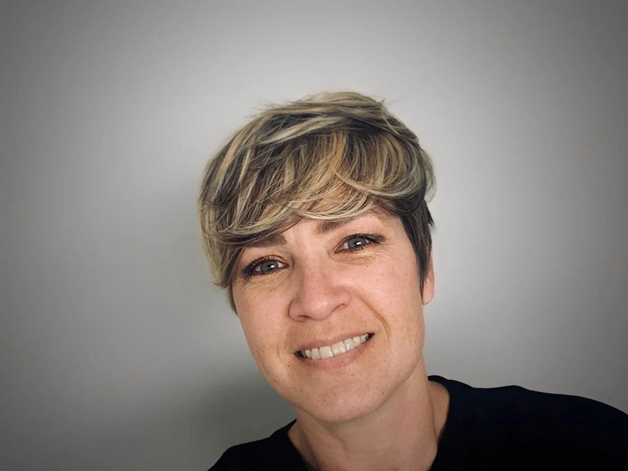 Portrait of woman smiling at the camera against a light gray background.