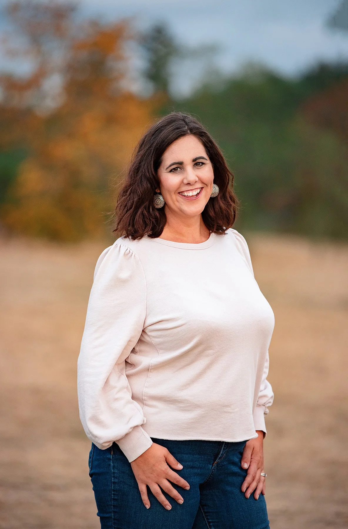 Professional outdoor headshot of a coach and podcast guest standing in a field at sunset.