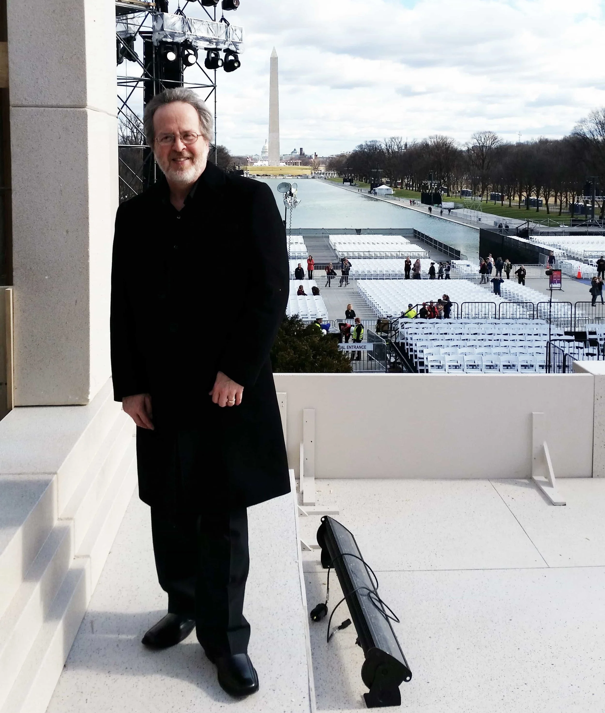 Man stands in coat outside the Lincoln Memorial in Washington, D.C. with the monomument in the background.