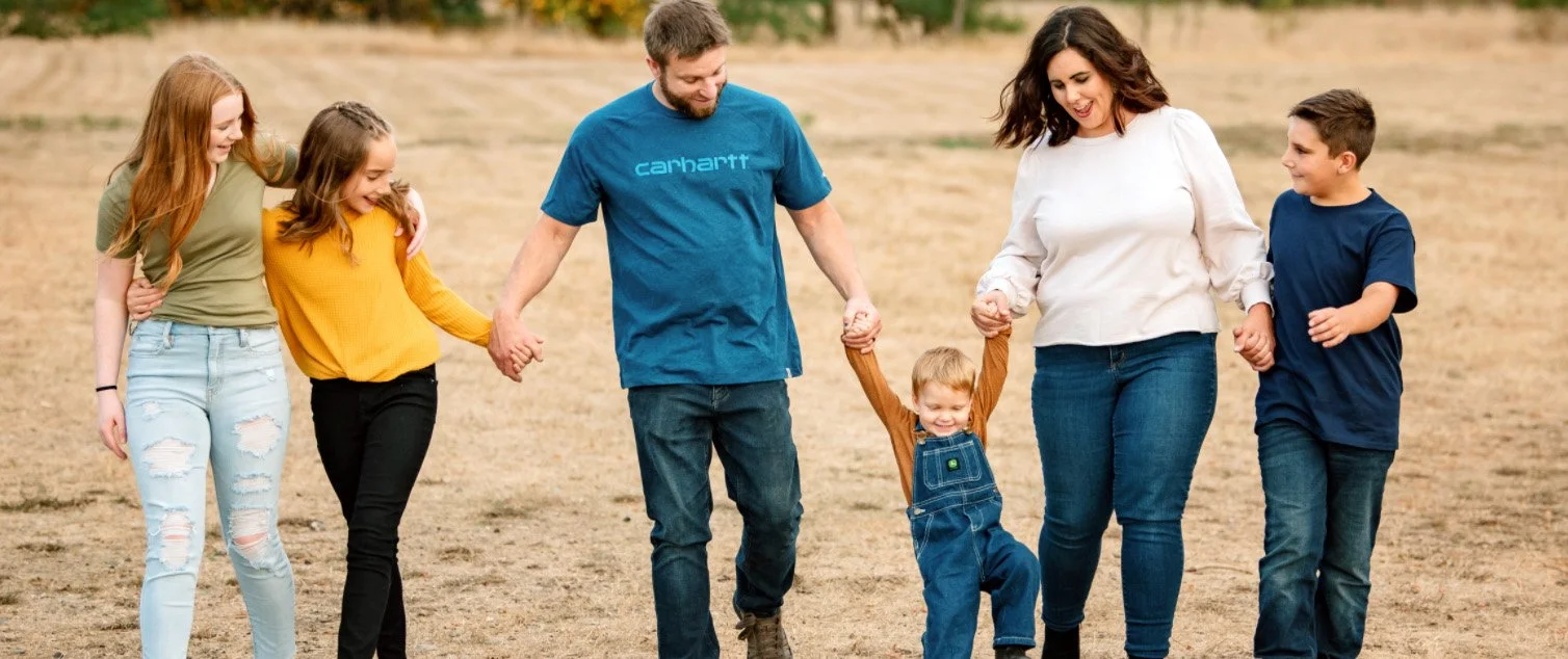Coach and mother walking with her family in an open field during a candid family portrait session.