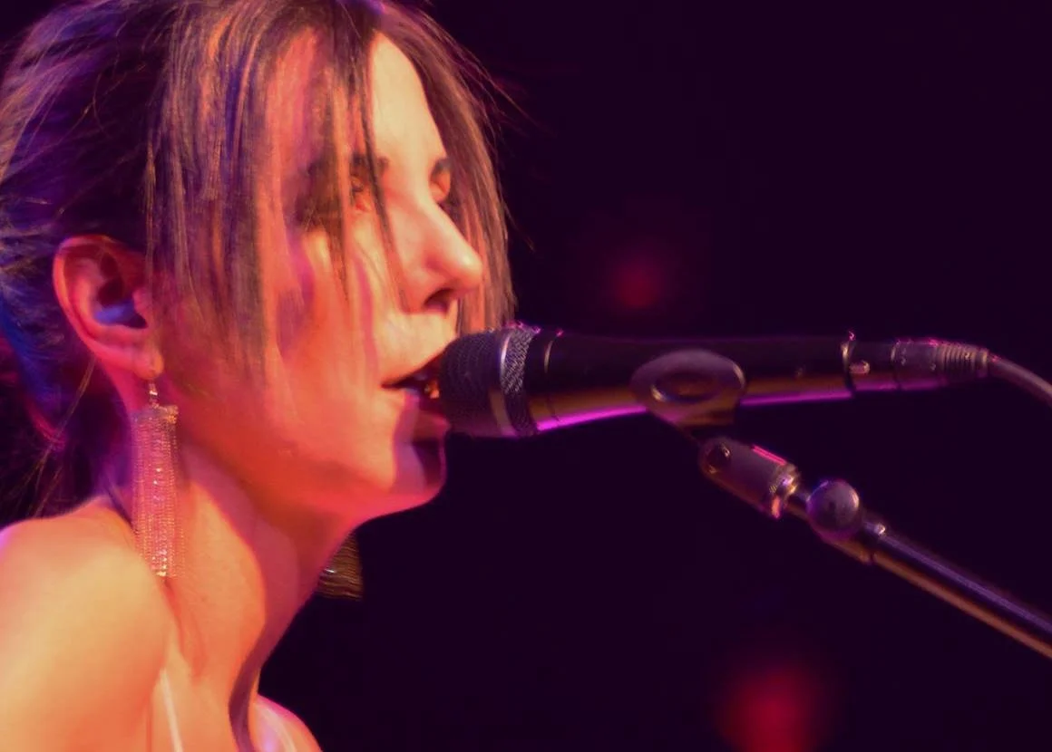 Singer performing into a microphone during a live music performance.