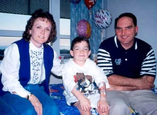 Family gathered around a young boy during a hospital stay, sharing a hopeful moment together.