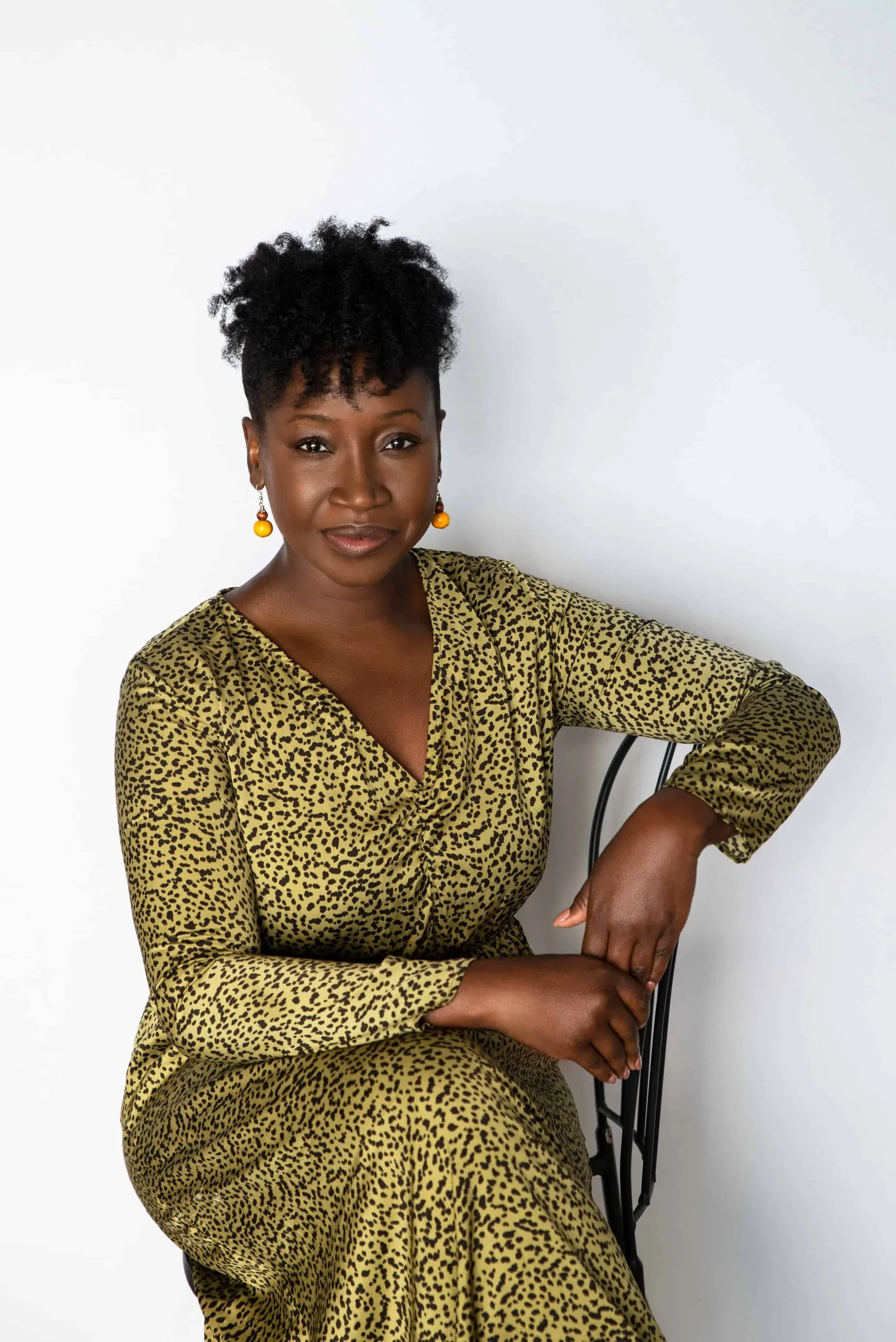 young black woman in leopard print dress sits on a chair