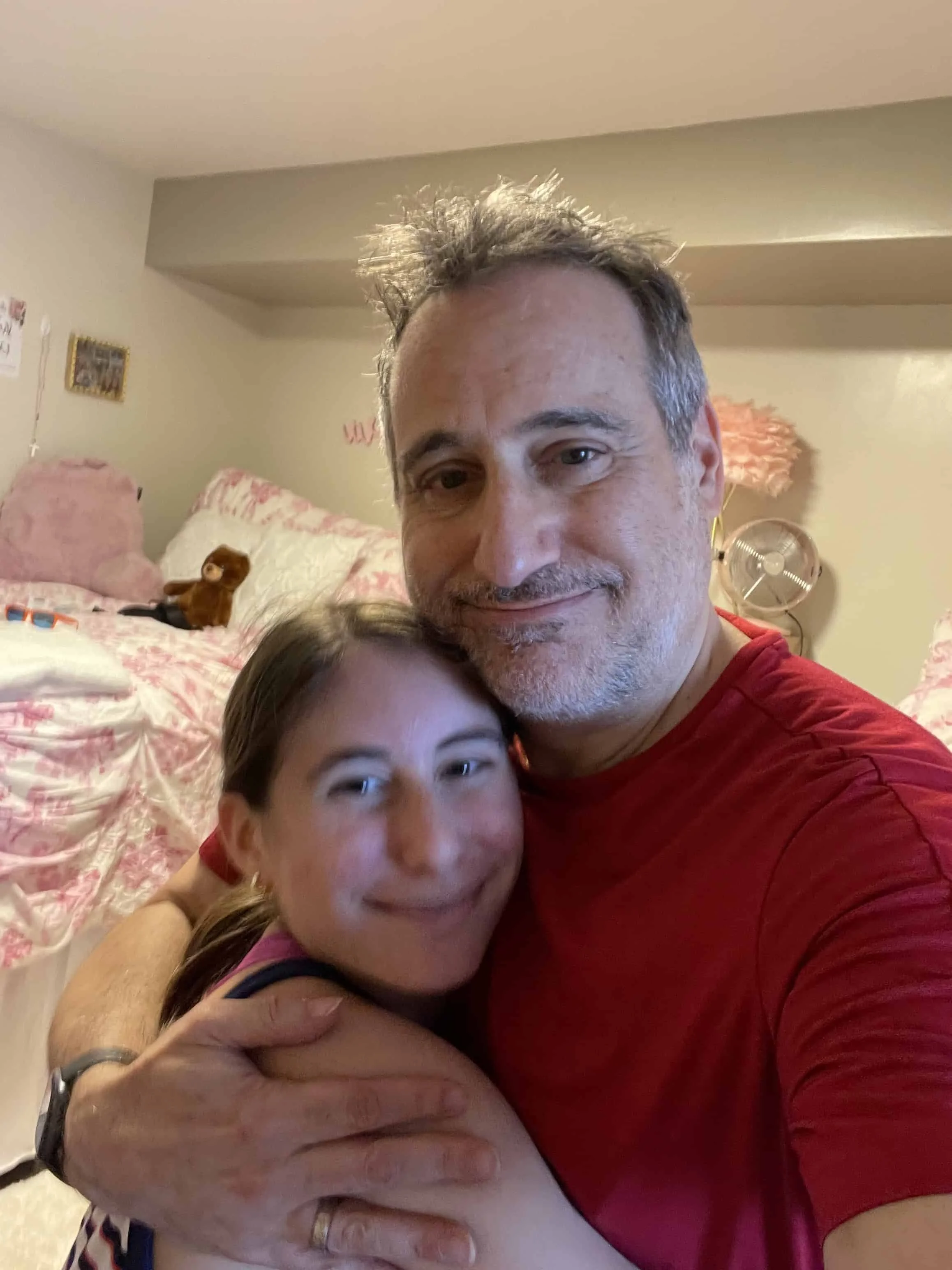 Father and teenager hugging and smiling while taking a selfie.