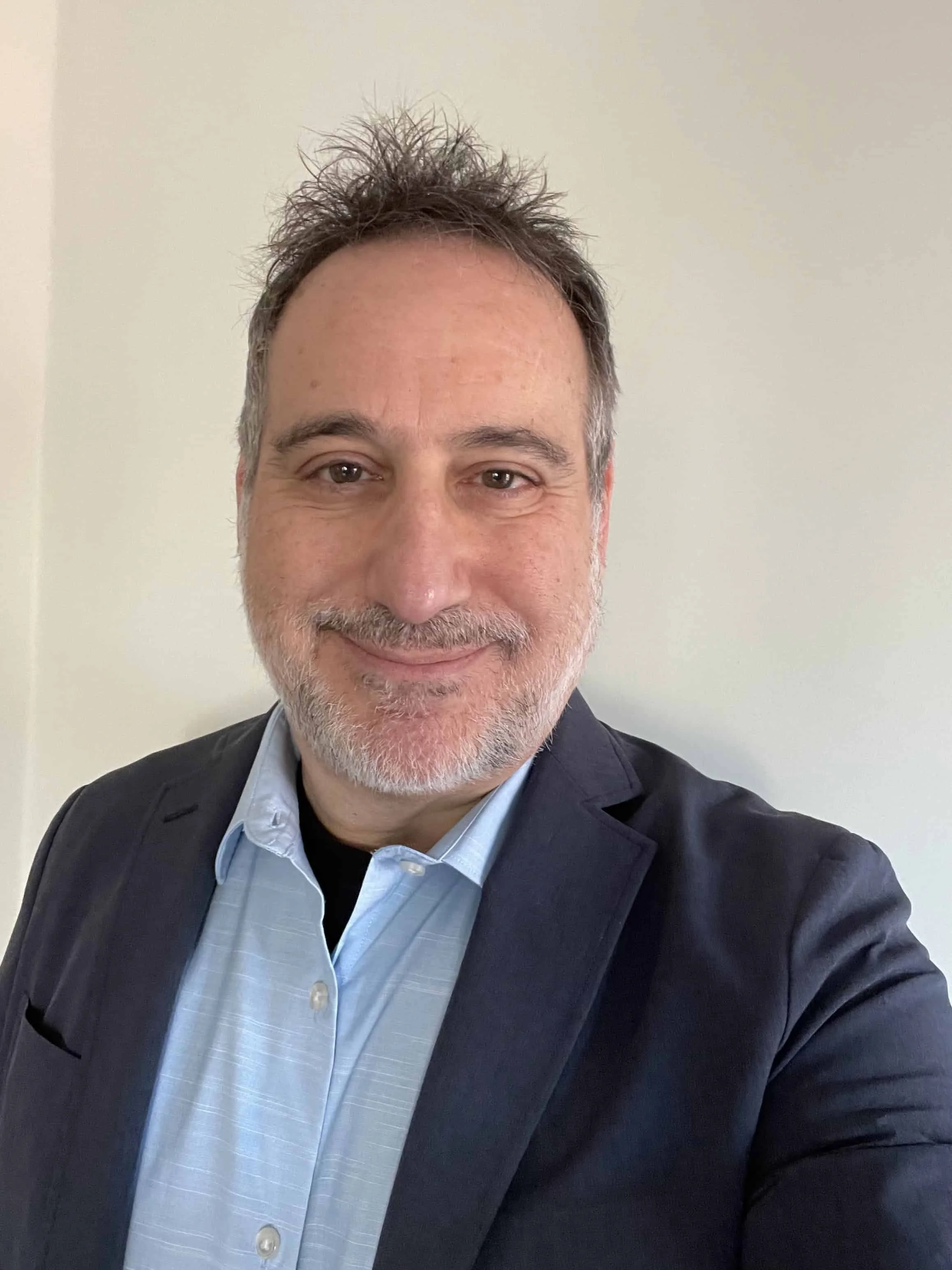 self portrait of a smiling man with a light blue shirt and navy sports coat
