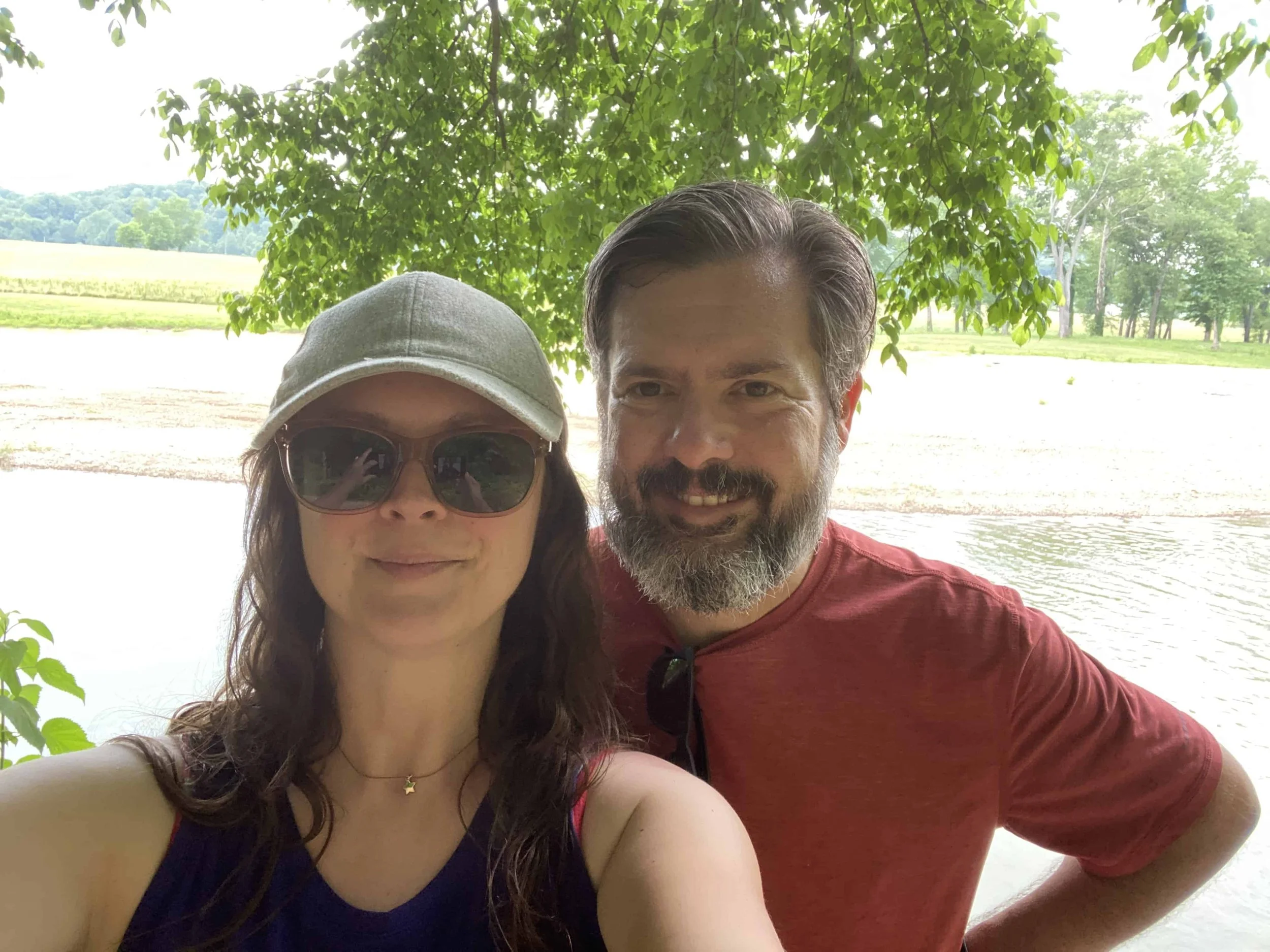 Man and woman pose together as they hike along a river.
