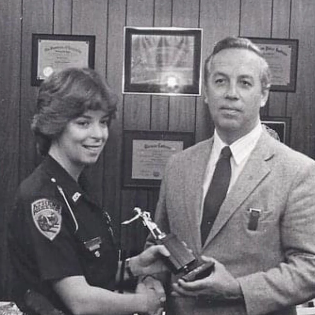 Young woman in a police uniform receiving an award during her early career as a police officer.