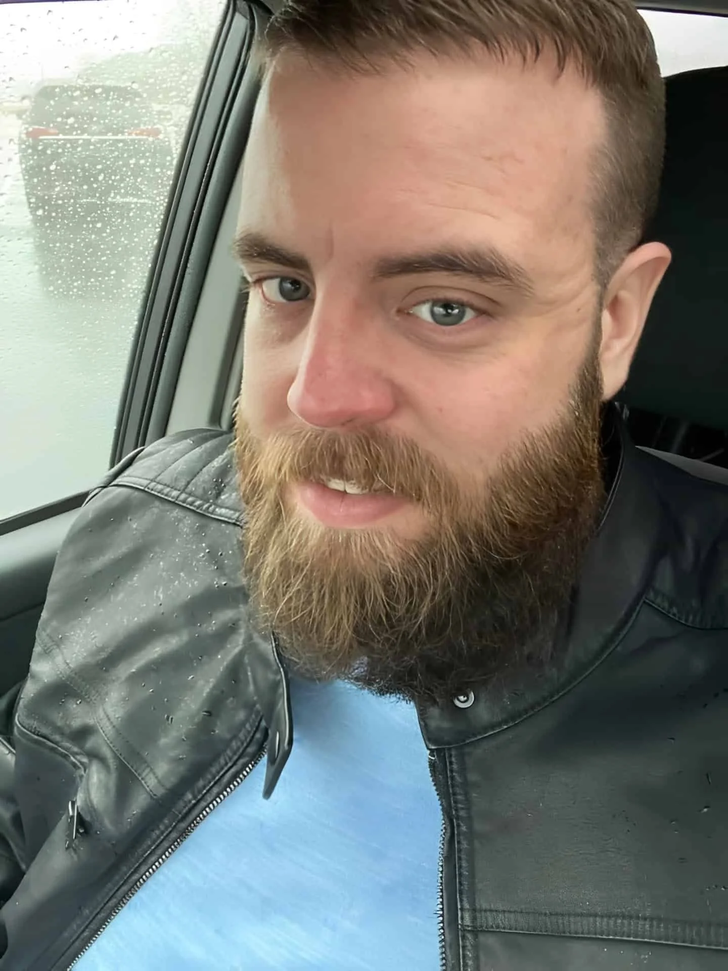 Close-up portrait of a bearded man in a car following a major weight loss transformation.