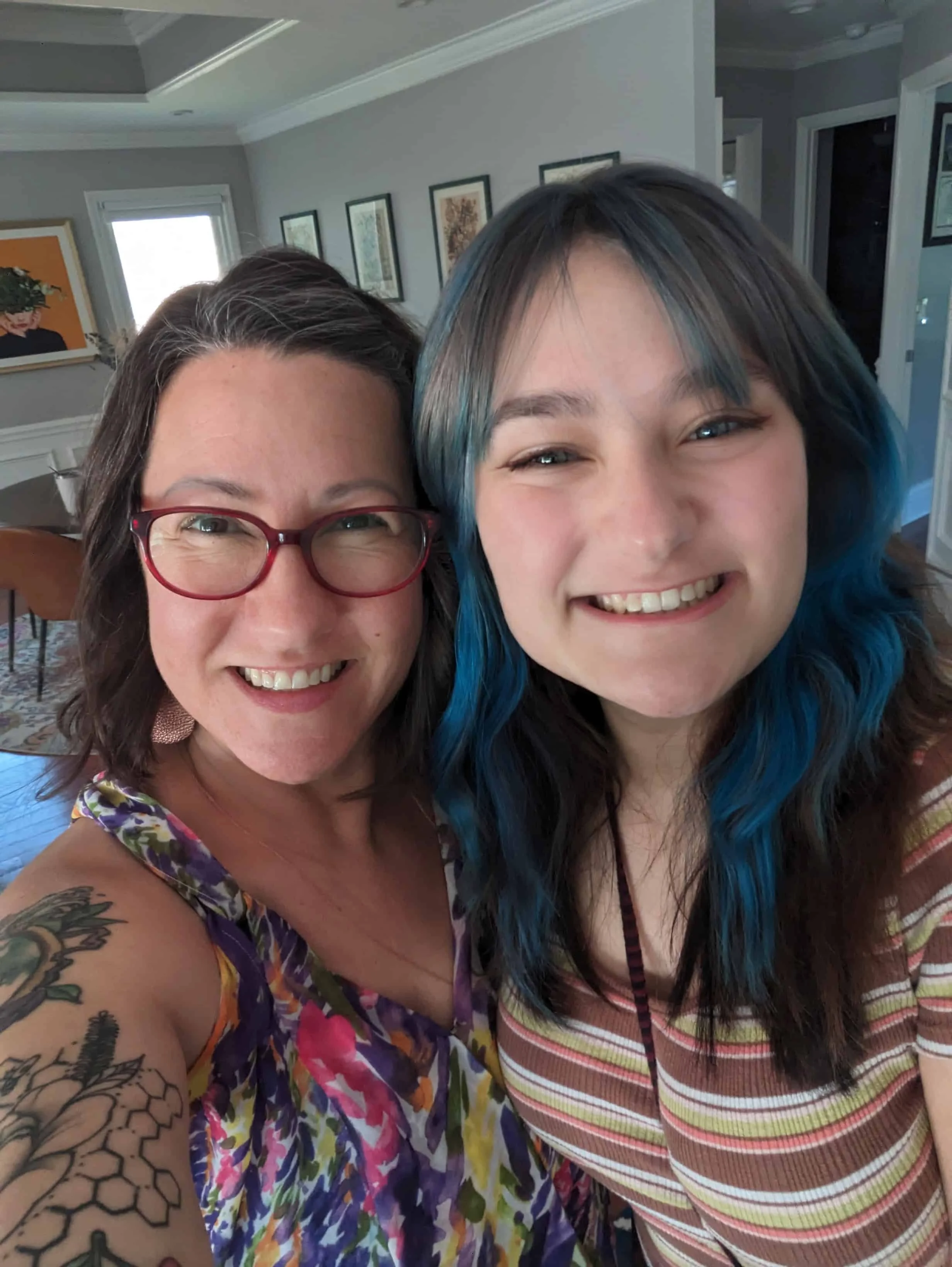 Woman and her teenage daughter smiling together as they take a selfie.