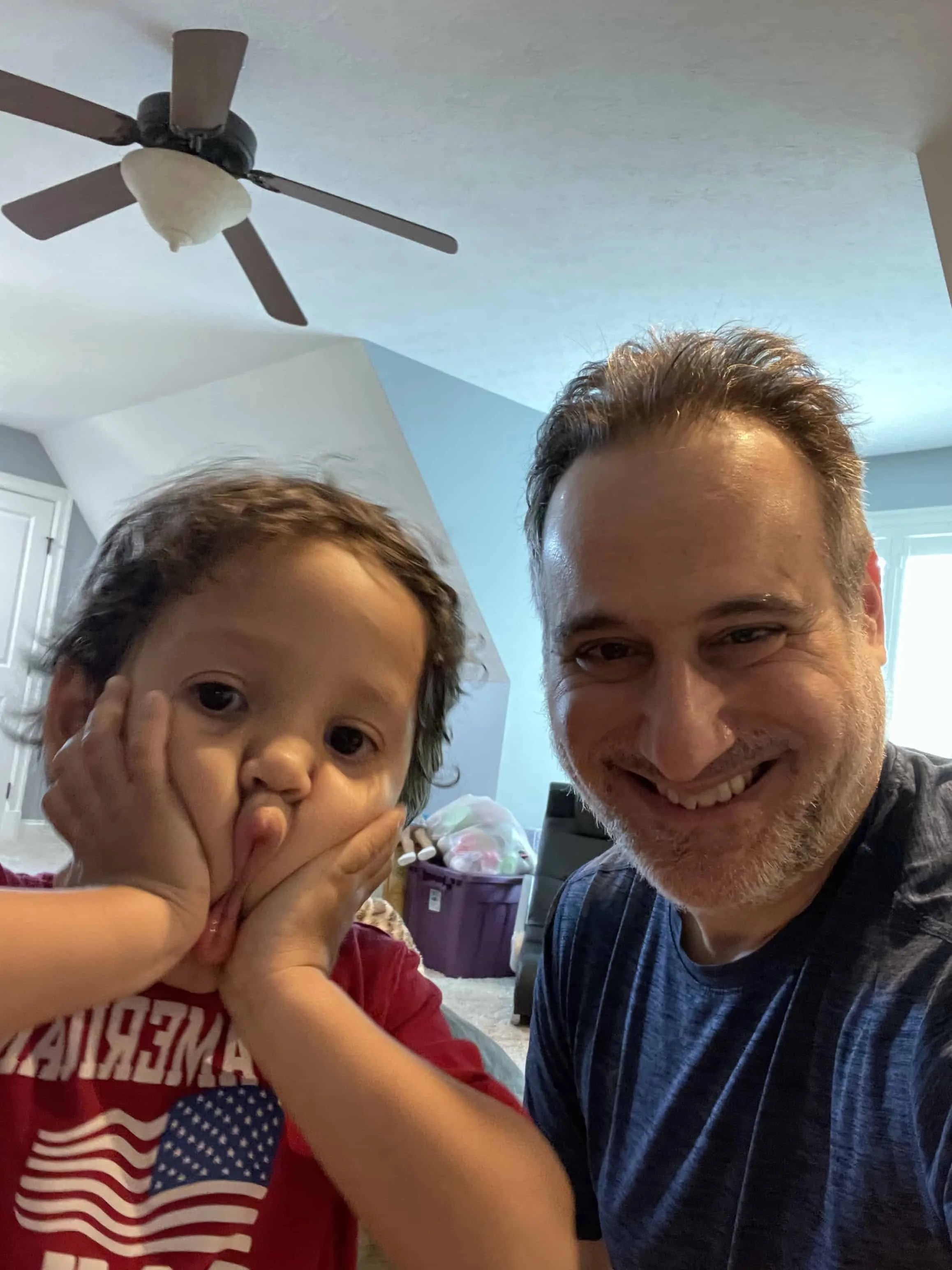 Man and young boy presses his face together in a playful, silly expression.