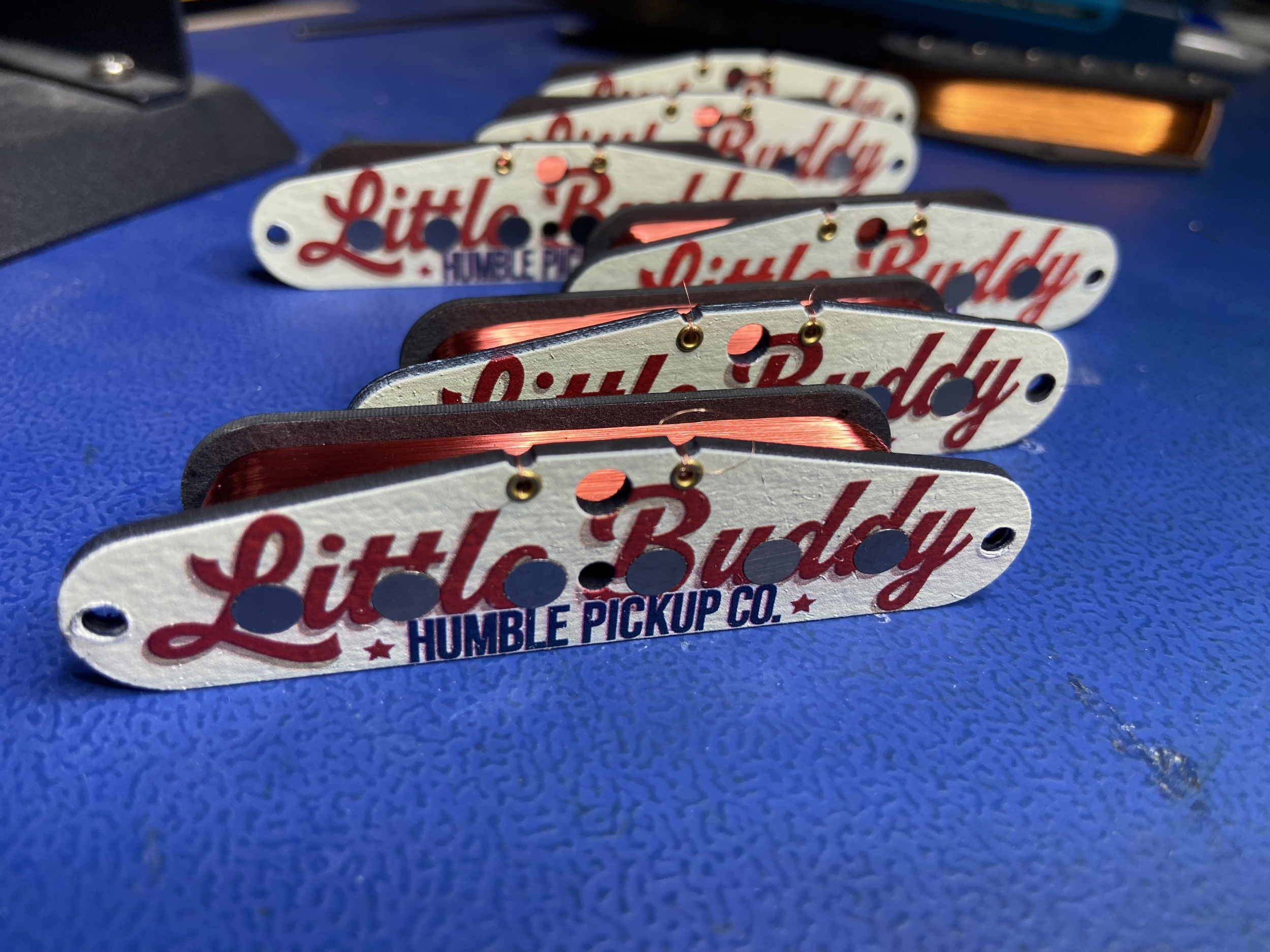 Close-up of telecaster neck pickup bobbins with red, white, and navy colors, labeled "Little Buddy" and "Humble Pickup Co." on the flatwork.