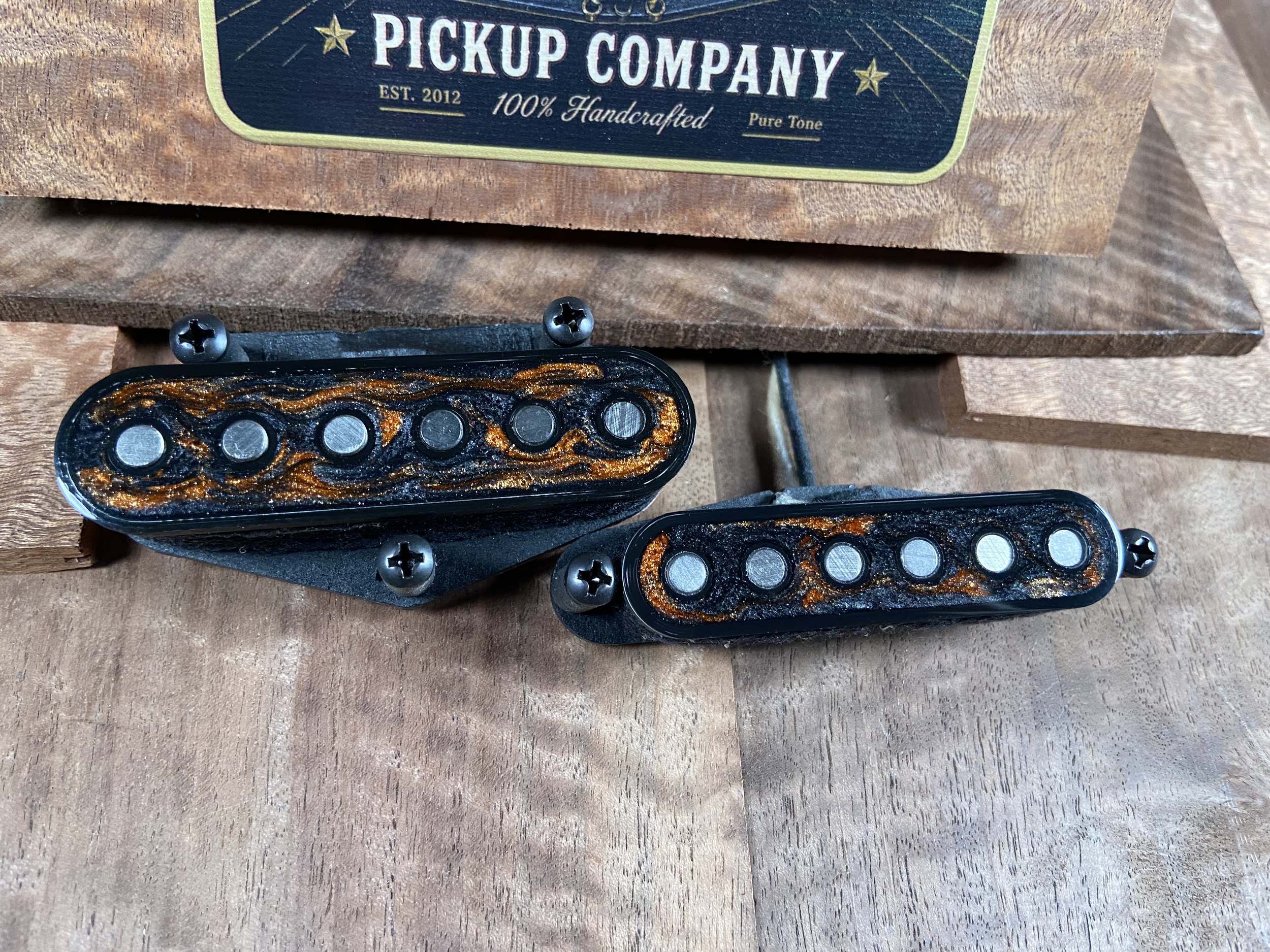 Close-up of electric guitar pickups with a box labeled 'Pickup Company' in the background.