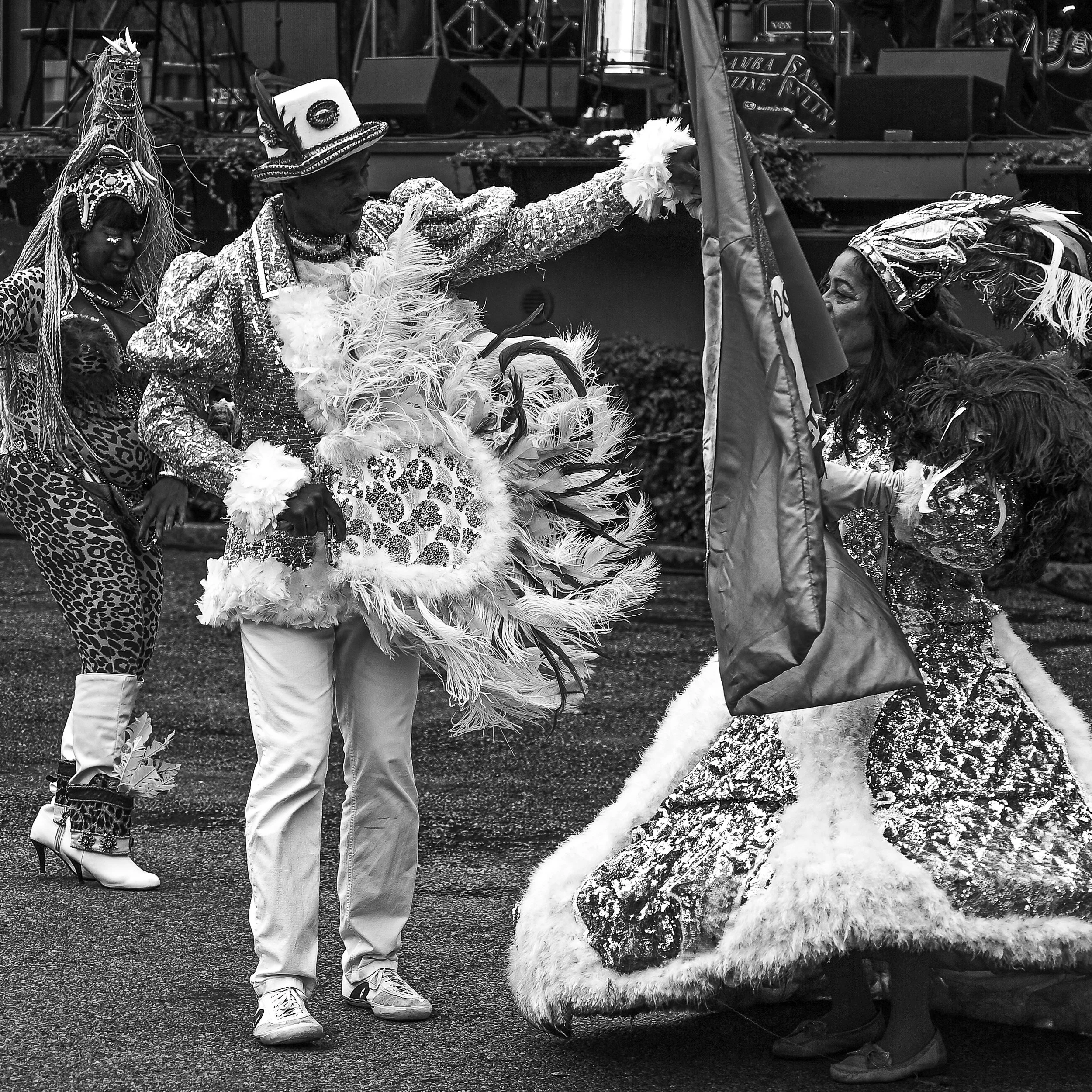People dressed in elaborate costumes, participating in a parade or celebration, with one person holding a flag.