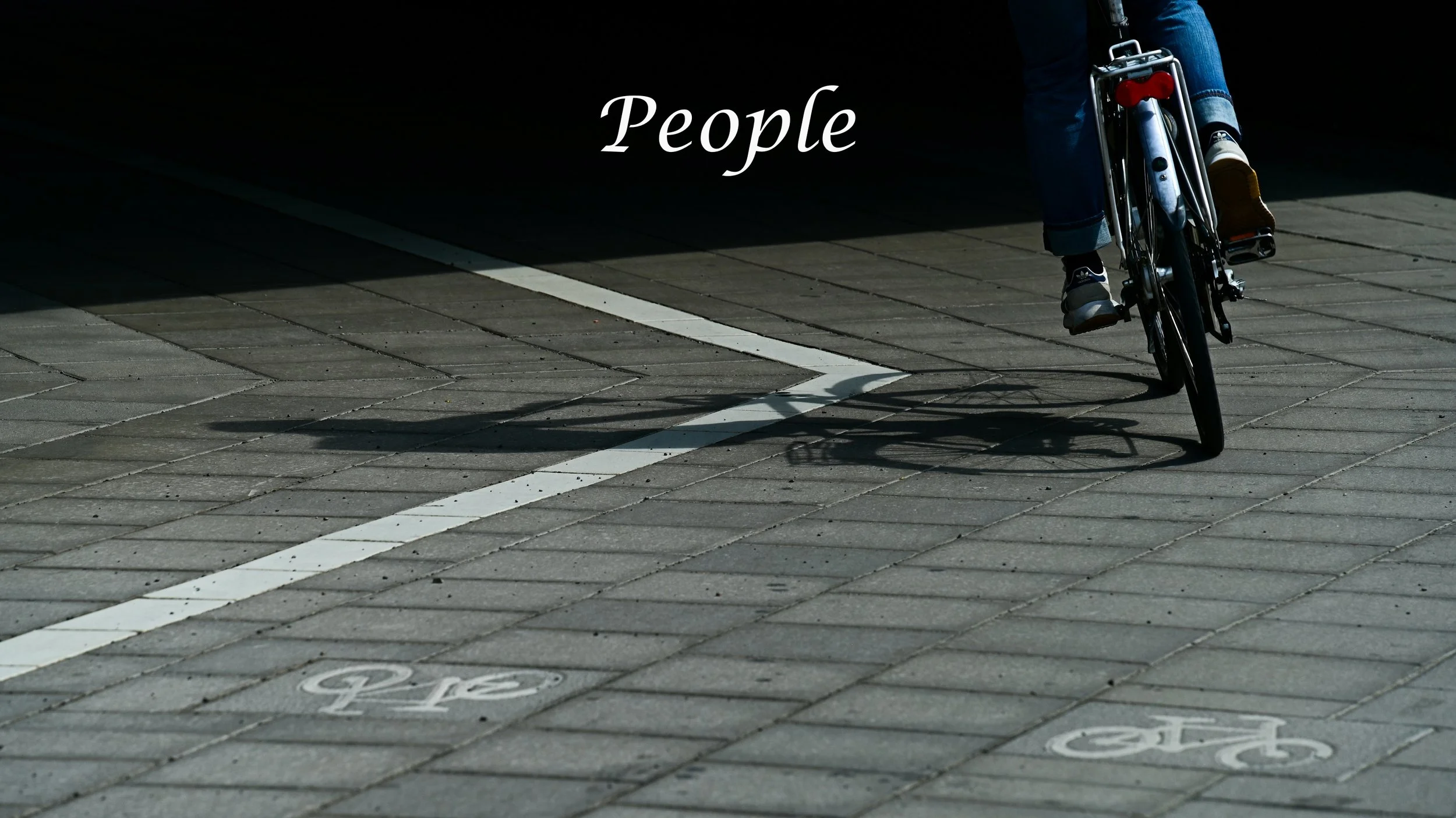 A person riding a bicycle on a paved bike lane with bicycle symbols, casting a shadow, under the word 'People' written on the image.