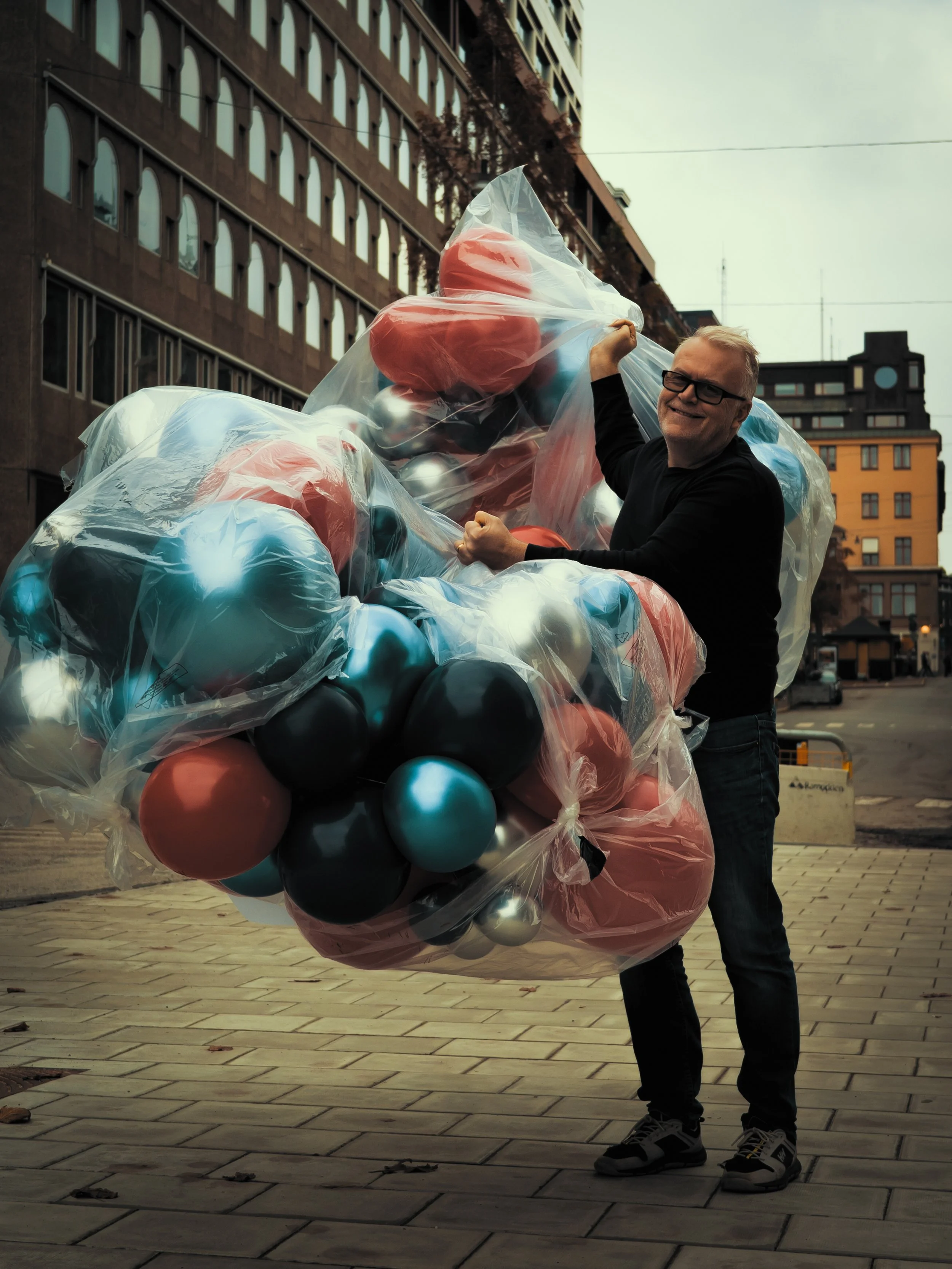 Man holding large bag of Christmas ornaments on city street.