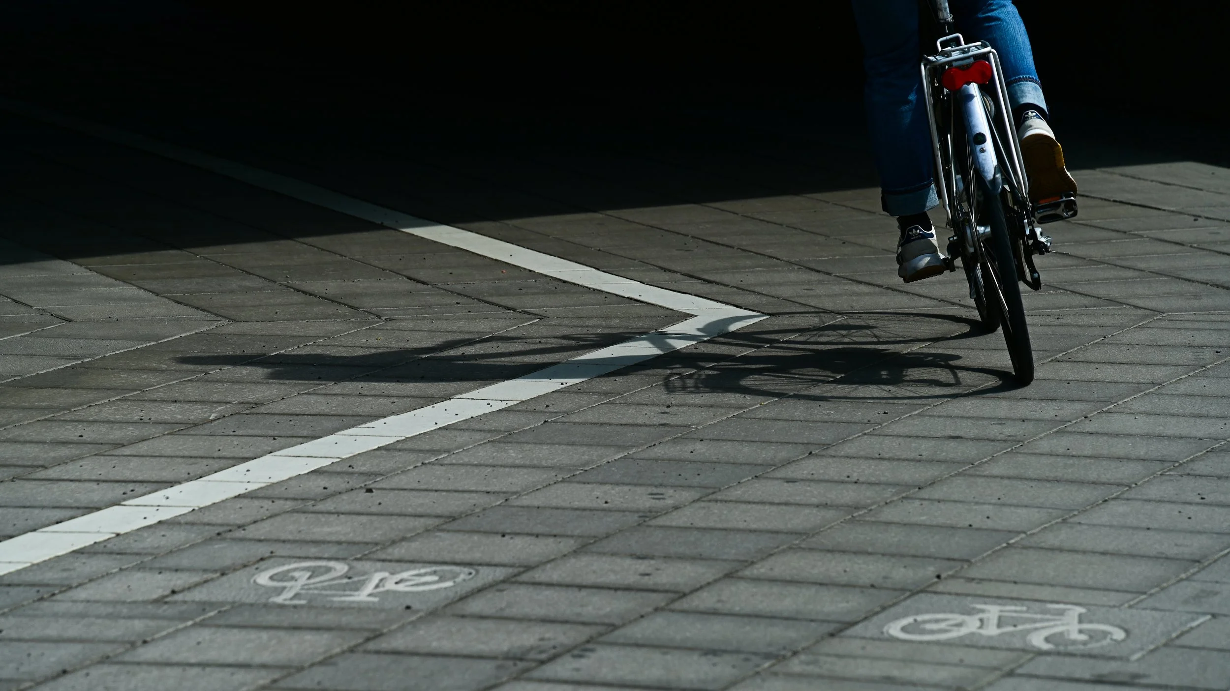 A person riding a bicycle in a designated bike lane on a paved street with bike lane markings and symbols.