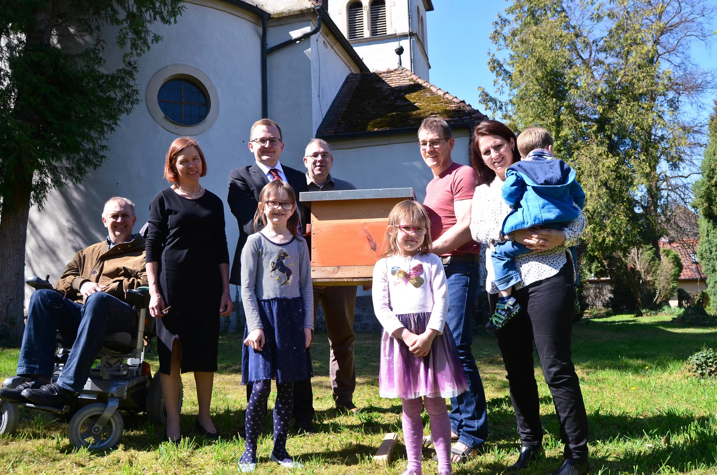 Pfarrer Tilman Schneider (4.v.l) und Antje Julke (2.v.l.), Vertrauensfrau und Umweltbeauftragte des Kirchenvorstandes, nehmen nach dem Gottesdienst mit Familie Jänsch und Frank Julke den ersten Bienenkasten von Edgar Weiß (3.v.r.) in Empfang.