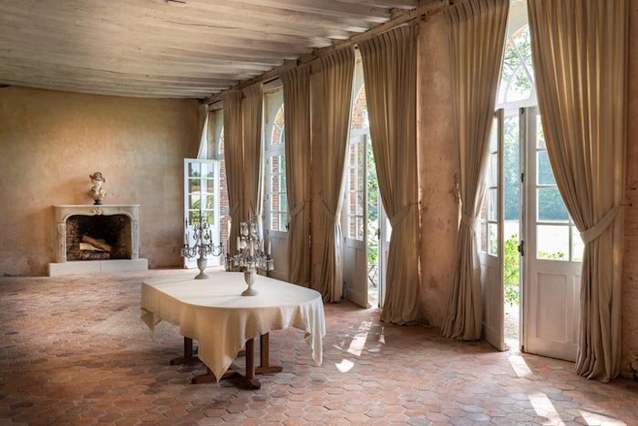 Inside the Orangerie, a large room with french doors and a cozy fireplace for rent in a French chateau.
