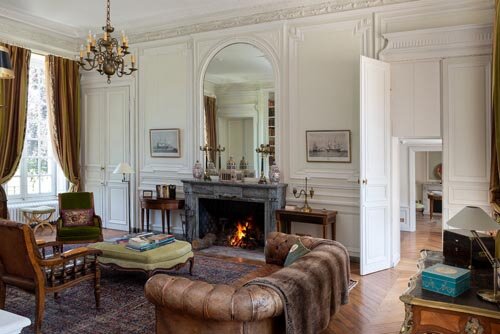 The library with a large fireplace, leather sofa and chairs available to book at Courtomer, a French chateau.