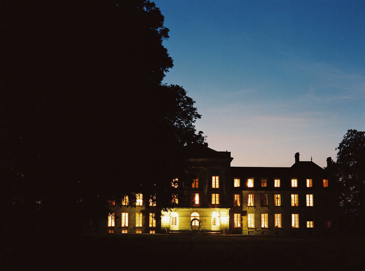A chateau with many light filled windows at night in Normandy, France.