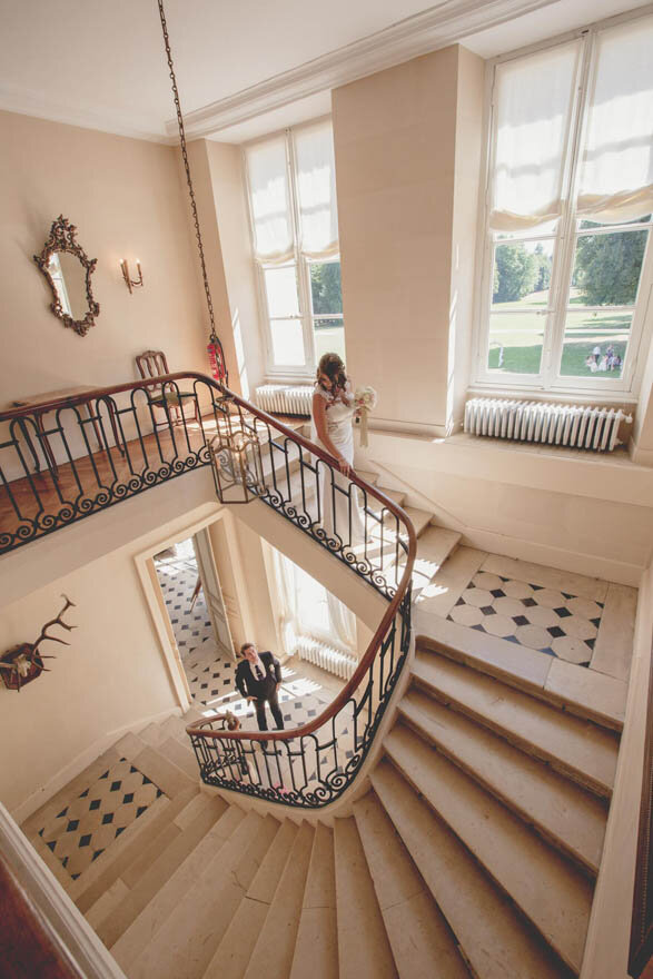 A bride and groom standing on a stone staircase at a French chateau wedding venue in Normandy, France.