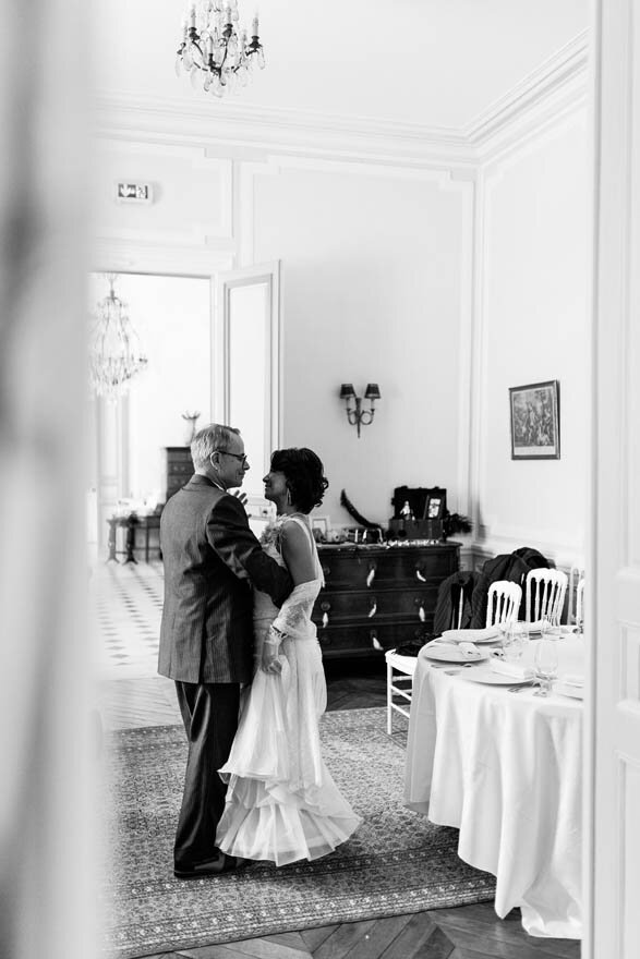 A black and white image of a bride and a man dancing at a French chateau during a wedding.