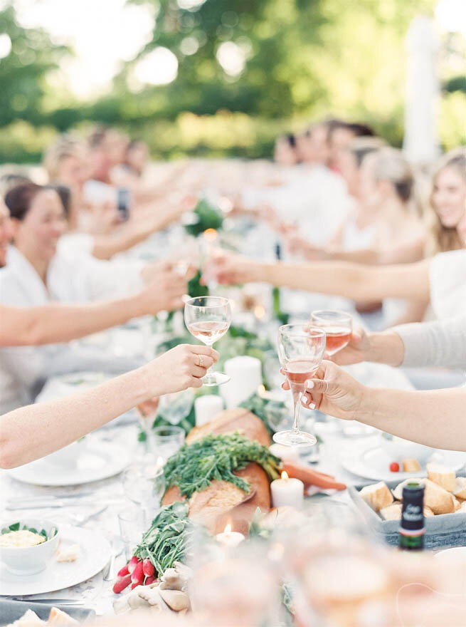 Wedding guests toasting at a long table at a French chateau wedding reception.