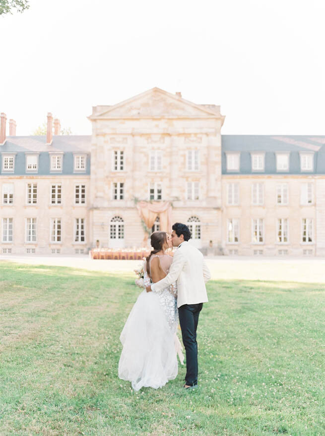 A bride and groom standing in front of Chateau de Courtomer, a beautful and intimate French wedding venue.