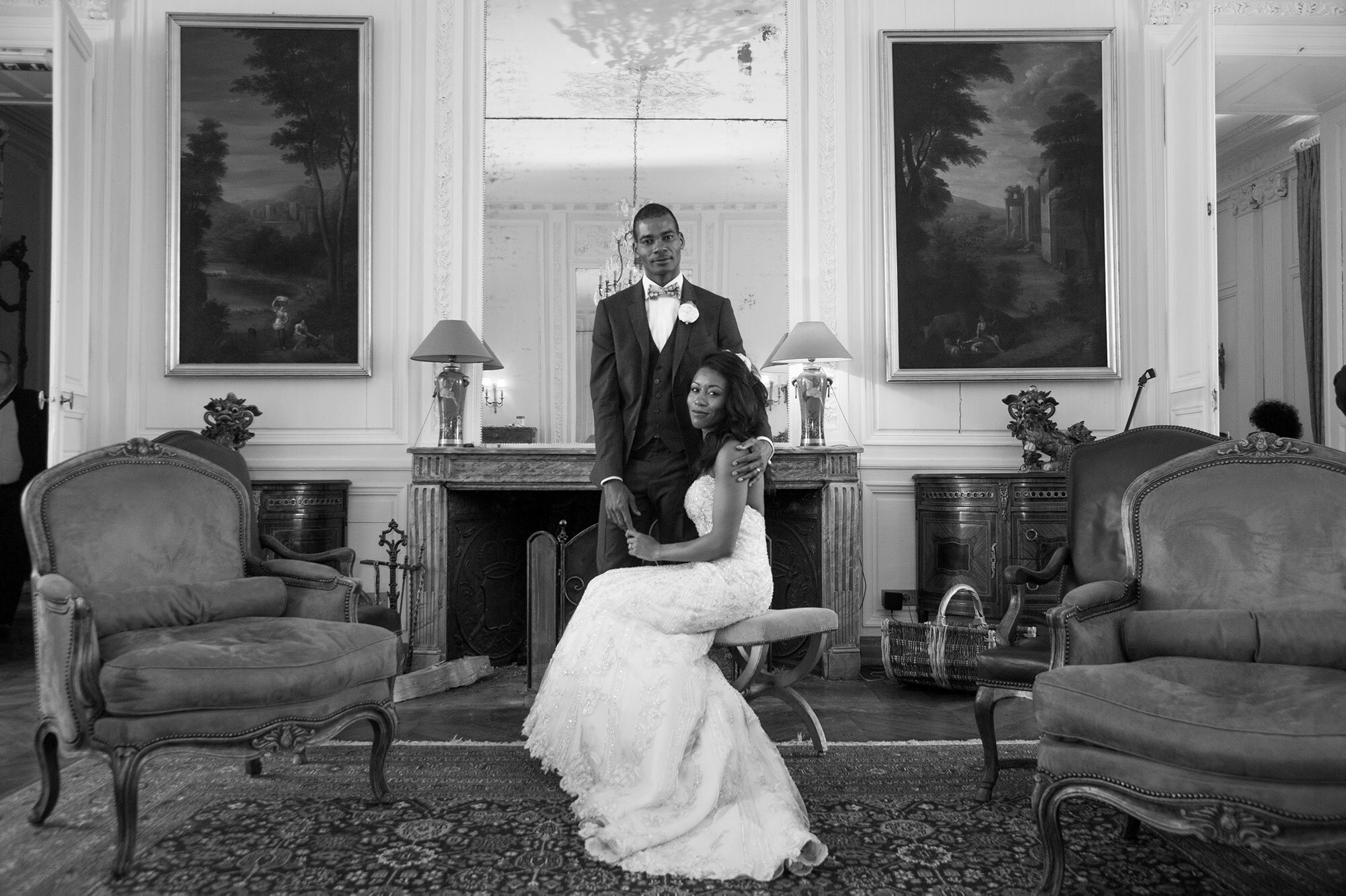 A black and white photo of a bride and groom posing in the living room of a grand chateau wedding venue.