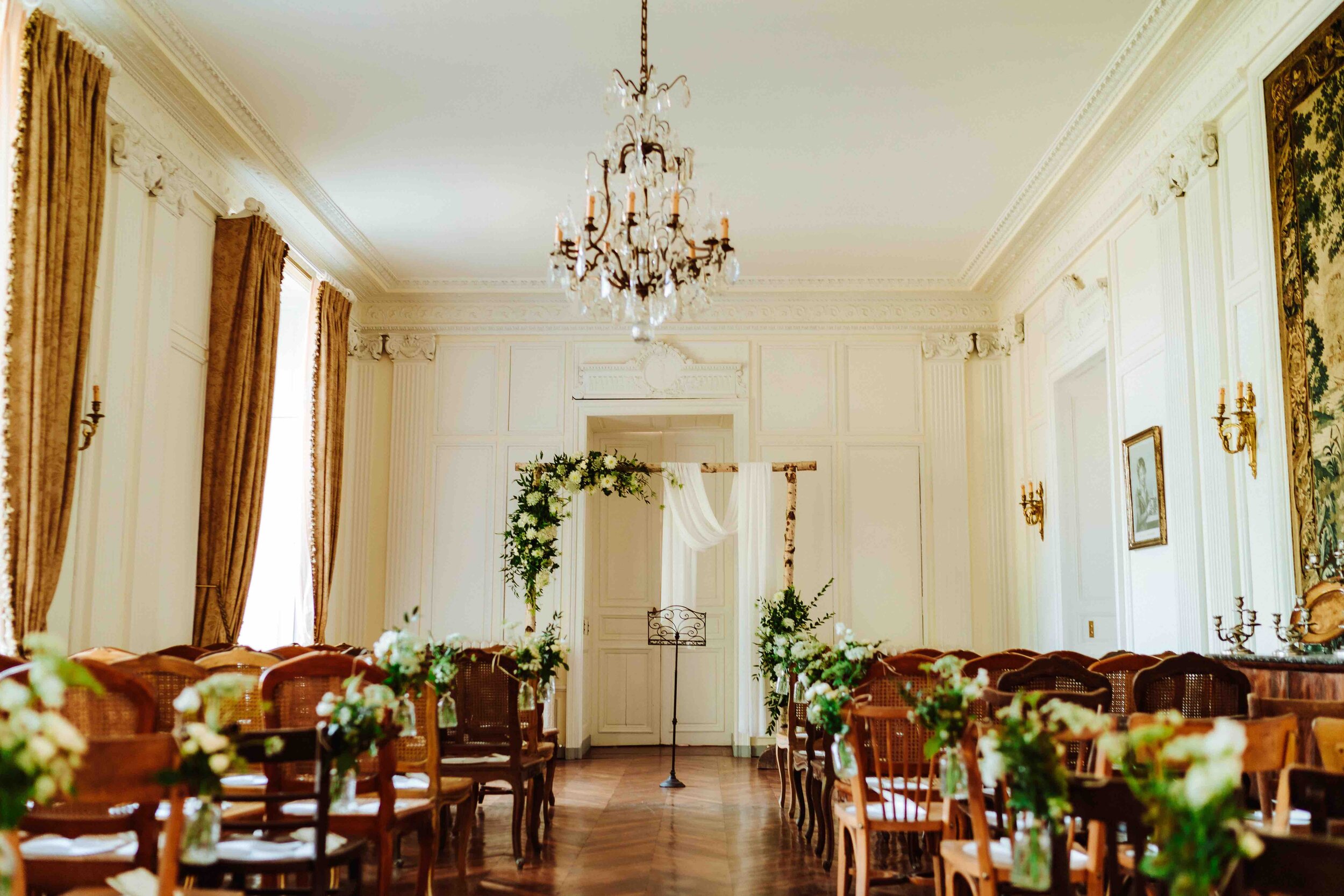 A room with a chandelier and stylish chairs decorated tastefully with flowers at a beautiful chateau wedding venue.