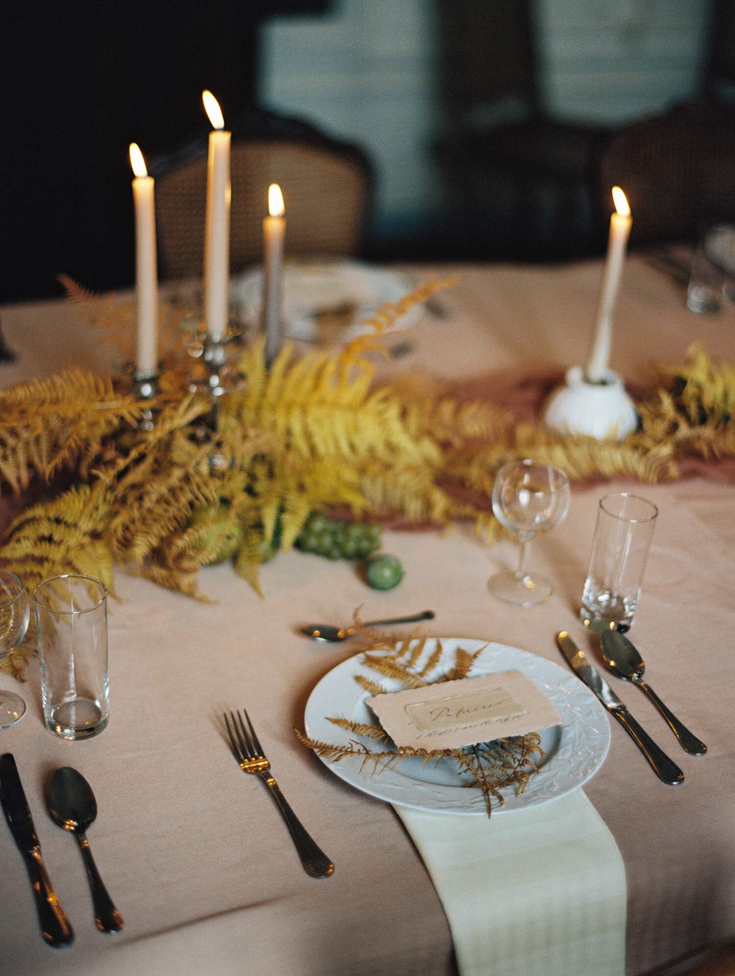 A table setting decorated with tall candles and ferns at Chateau de Courtomer, the perfect intimate french wedding venue.