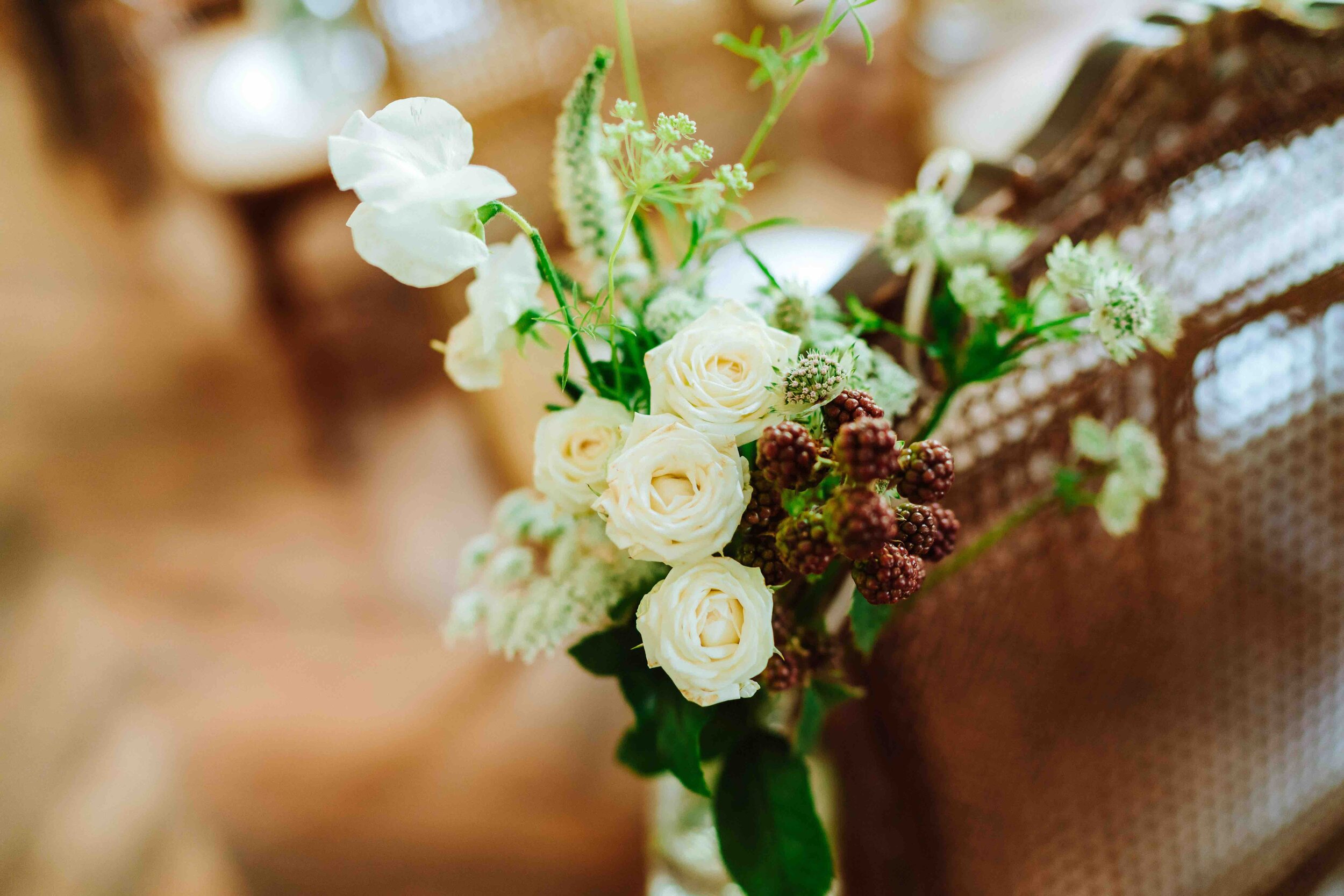 A white vase with flowers decorating a stylish wooden chair for a wedding at the chateau.