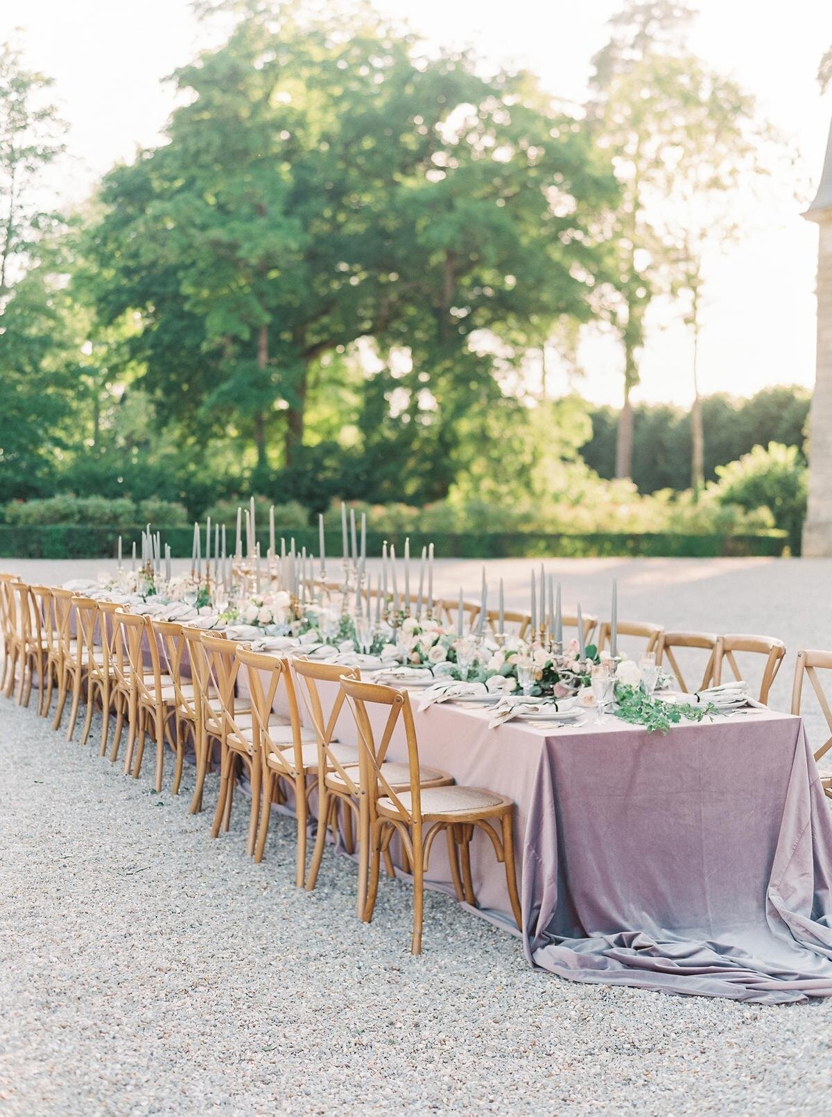 A long dining table set up in the courtyard for a french chateau wedding reception at Chateau de Courtomer.