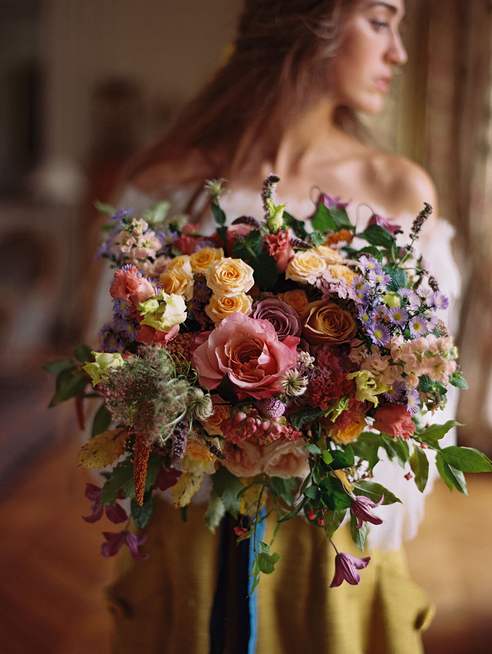 A woman holding a bouquet of flowers in a chateau wedding venue.
