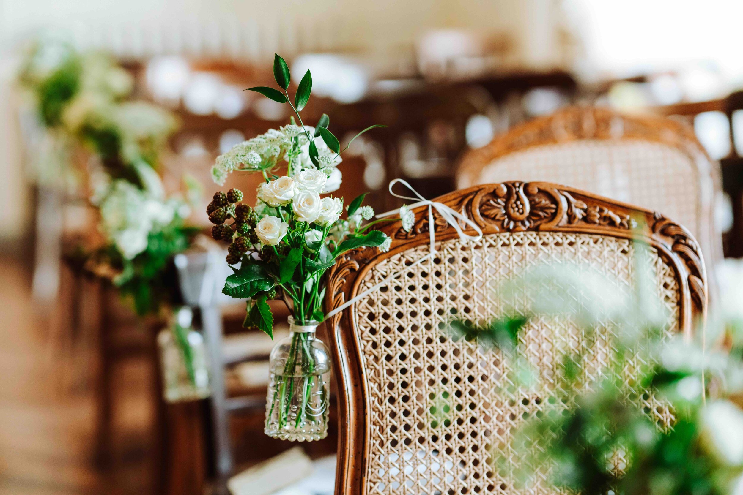 Wicker chairs decorated with pretty flowers at a wedding at Chateau de Courtomer in Normandy.