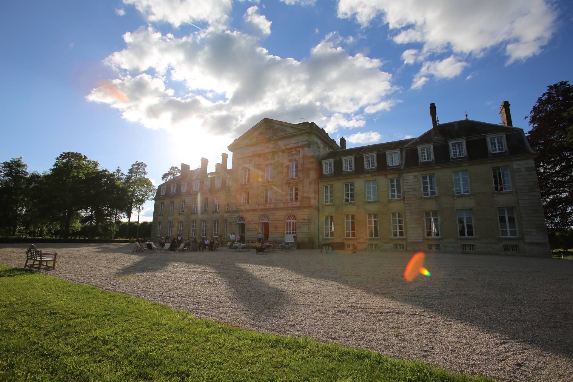Light streaming through clouds on the facade of Chateau de Courtomer, a venue for corporate team building activities in France.
